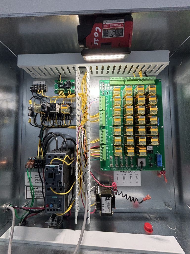 Electrical control panel with wiring, relays, and a red camera mounted inside a metal enclosure.