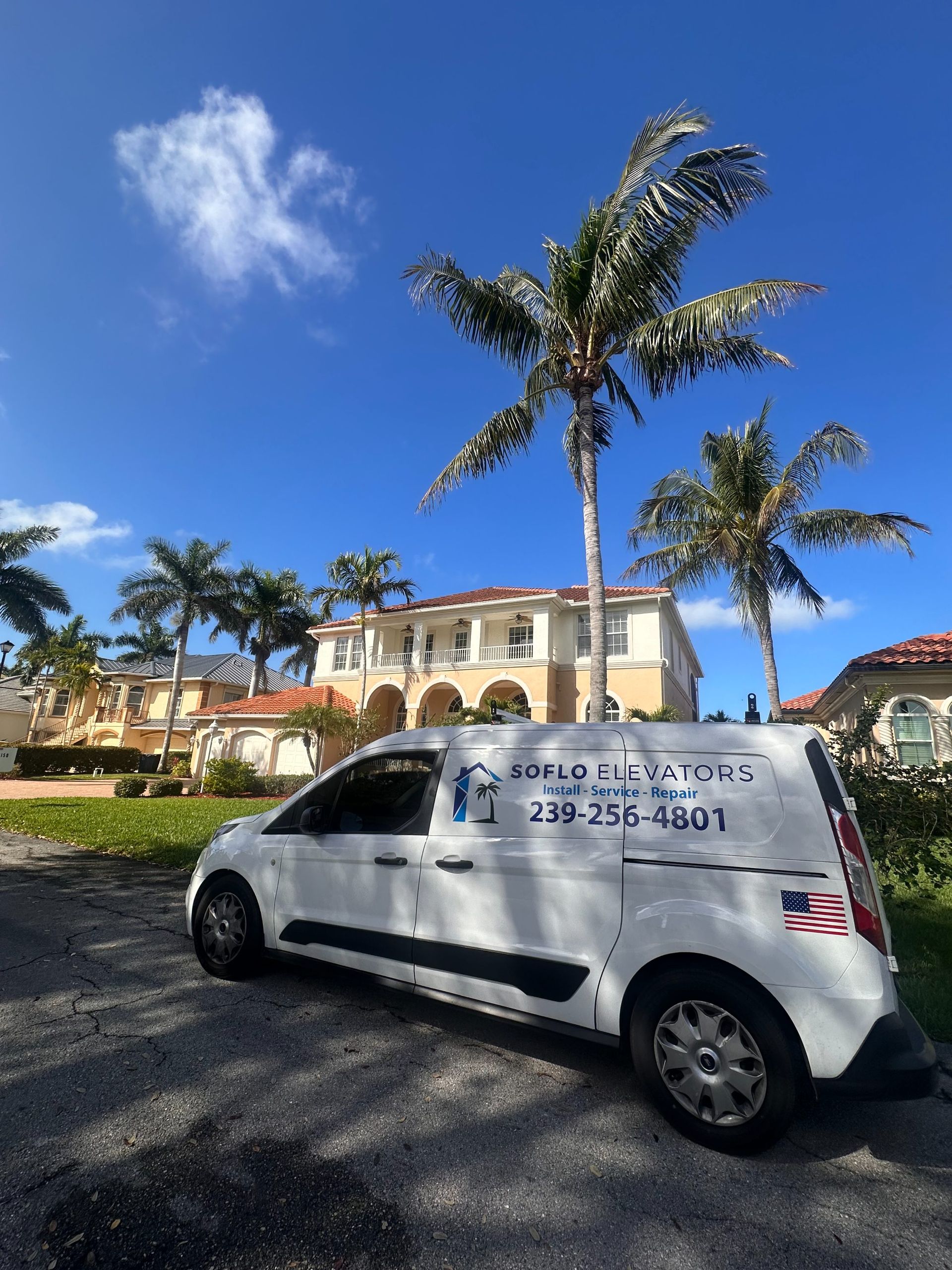 White van parked on gravel by a resort, with palm trees and blue sky in the background