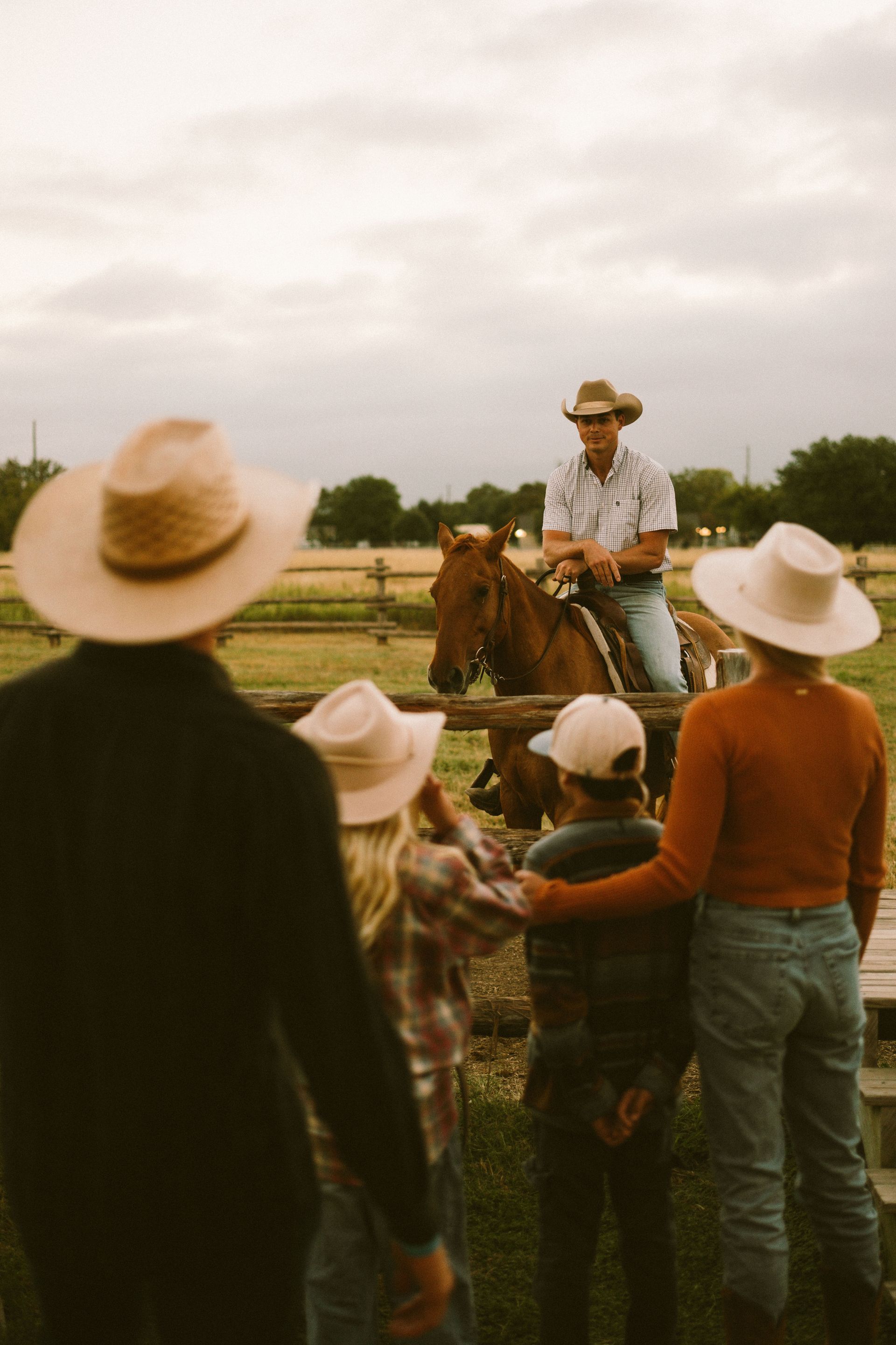 Five people on horseback at sunset overlooking a river.