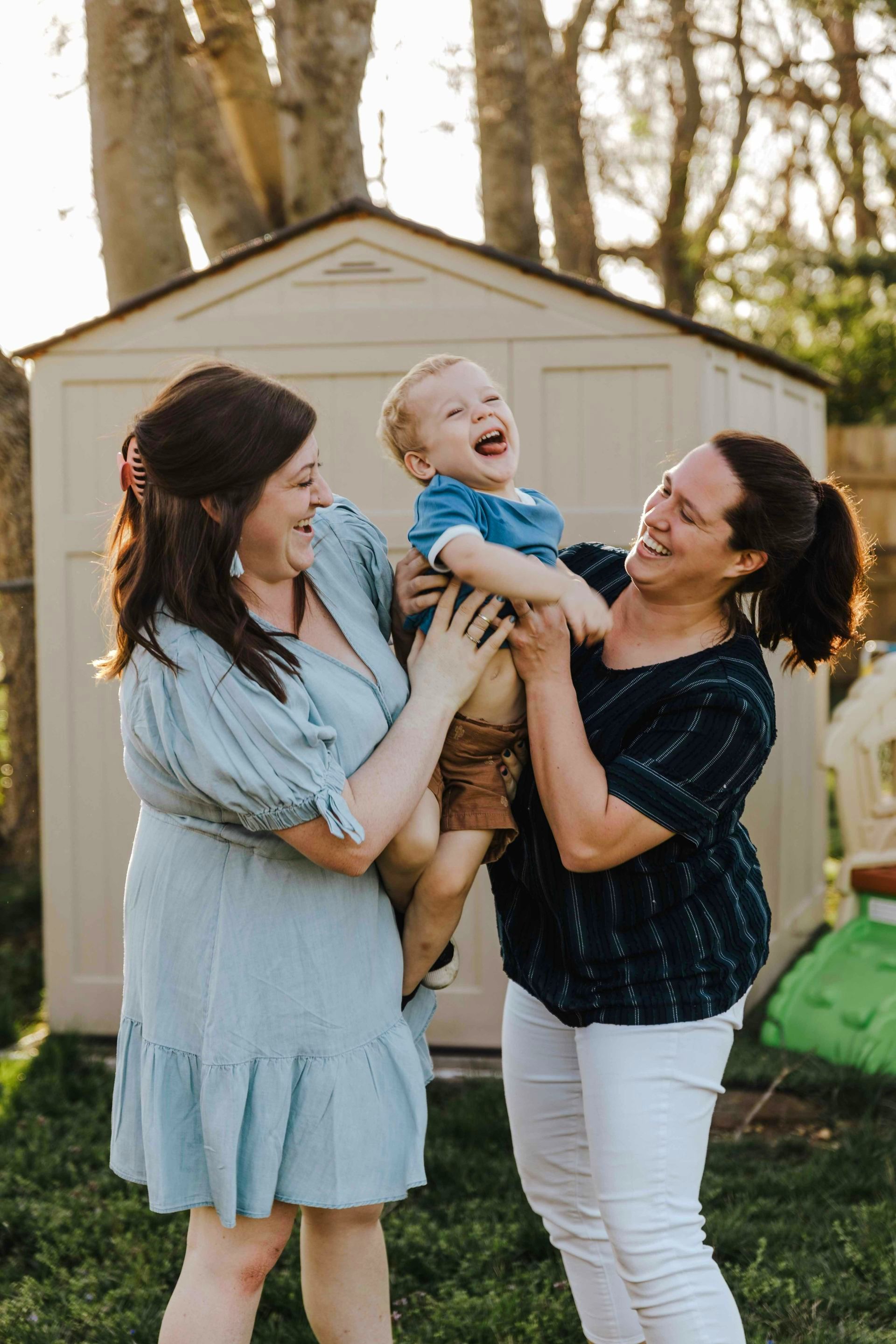 Two women holding a baby in front of a shed—clients of a reliable Houston law firm