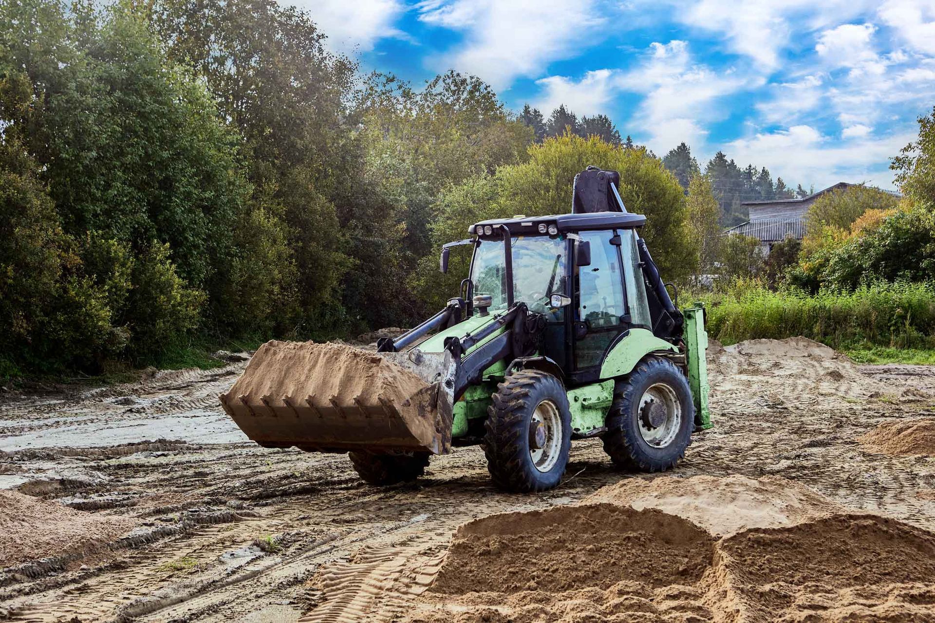A wheel-mounted earthmover spreading soil evenly to create a stable base for a construction site. A wheel-mounted earthmover spreading soil evenly to create a stable base for a construction site.