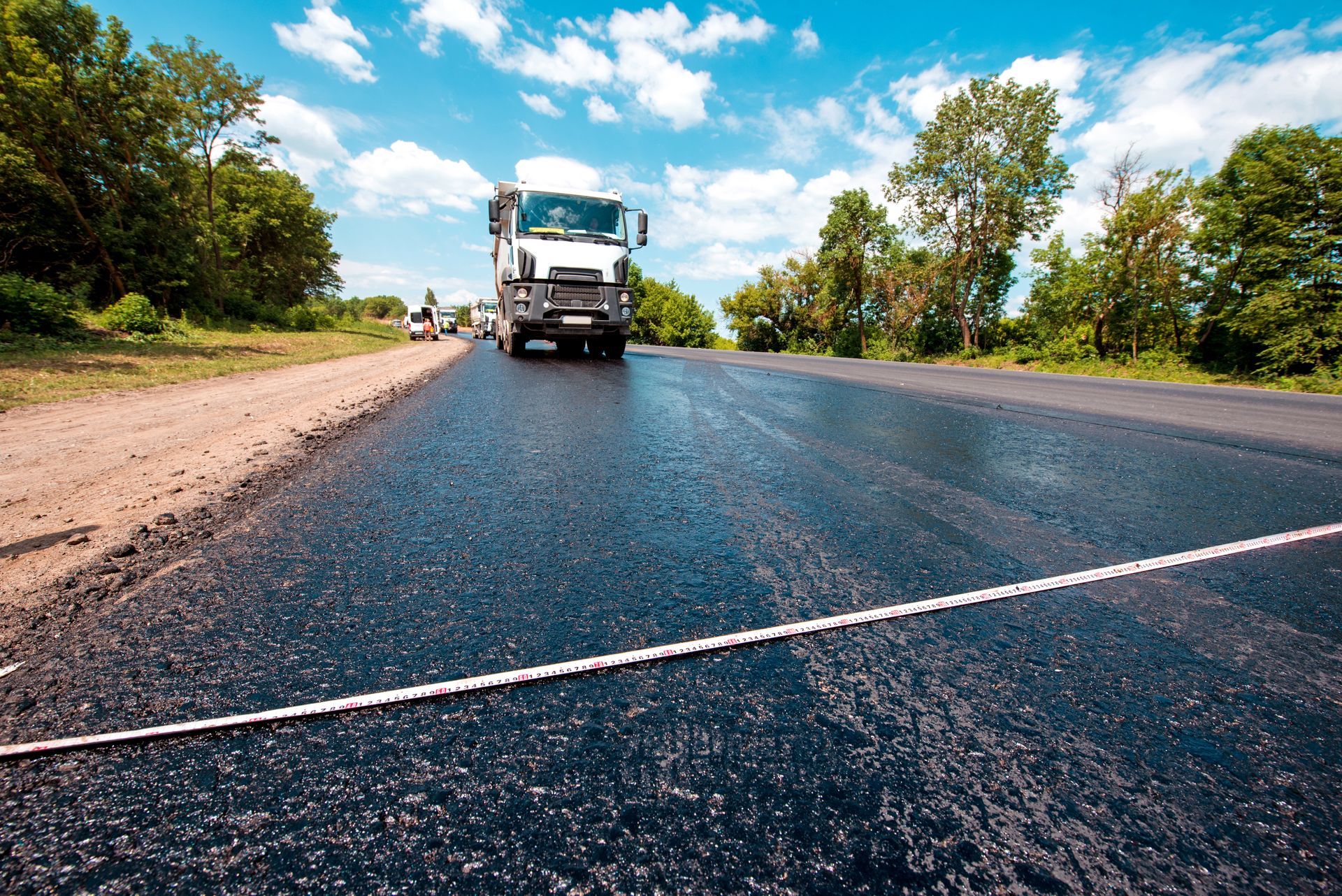 Centimetre tape for measuring length on a road, polished with bitumen on the background of trucks. Centimetre tape for measuring length on a road, polished with bitumen on the background of trucks.