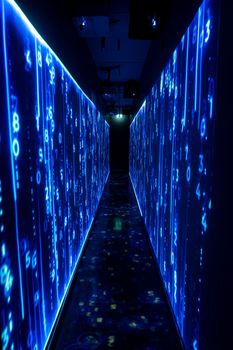 Pasillo de una sala de servidores iluminada en azul, con paneles de datos brillantes a ambos lados
