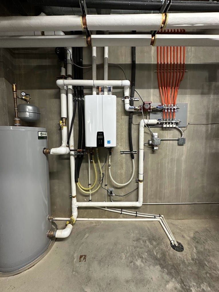 Utility room with water heater, white boiler unit, and pipes against a concrete wall.