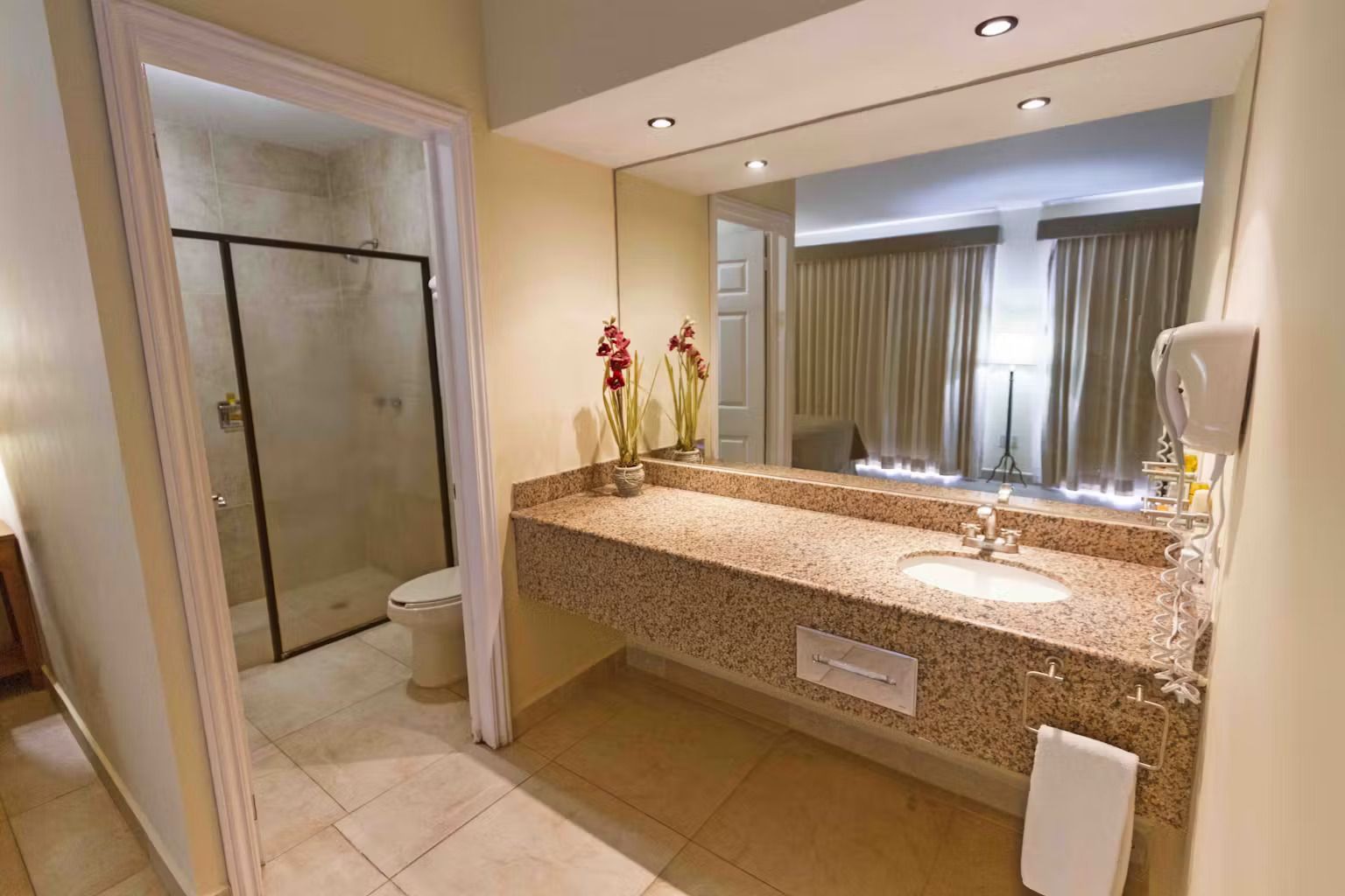 A bathroom in a hotel room with a sink , toilet and shower.