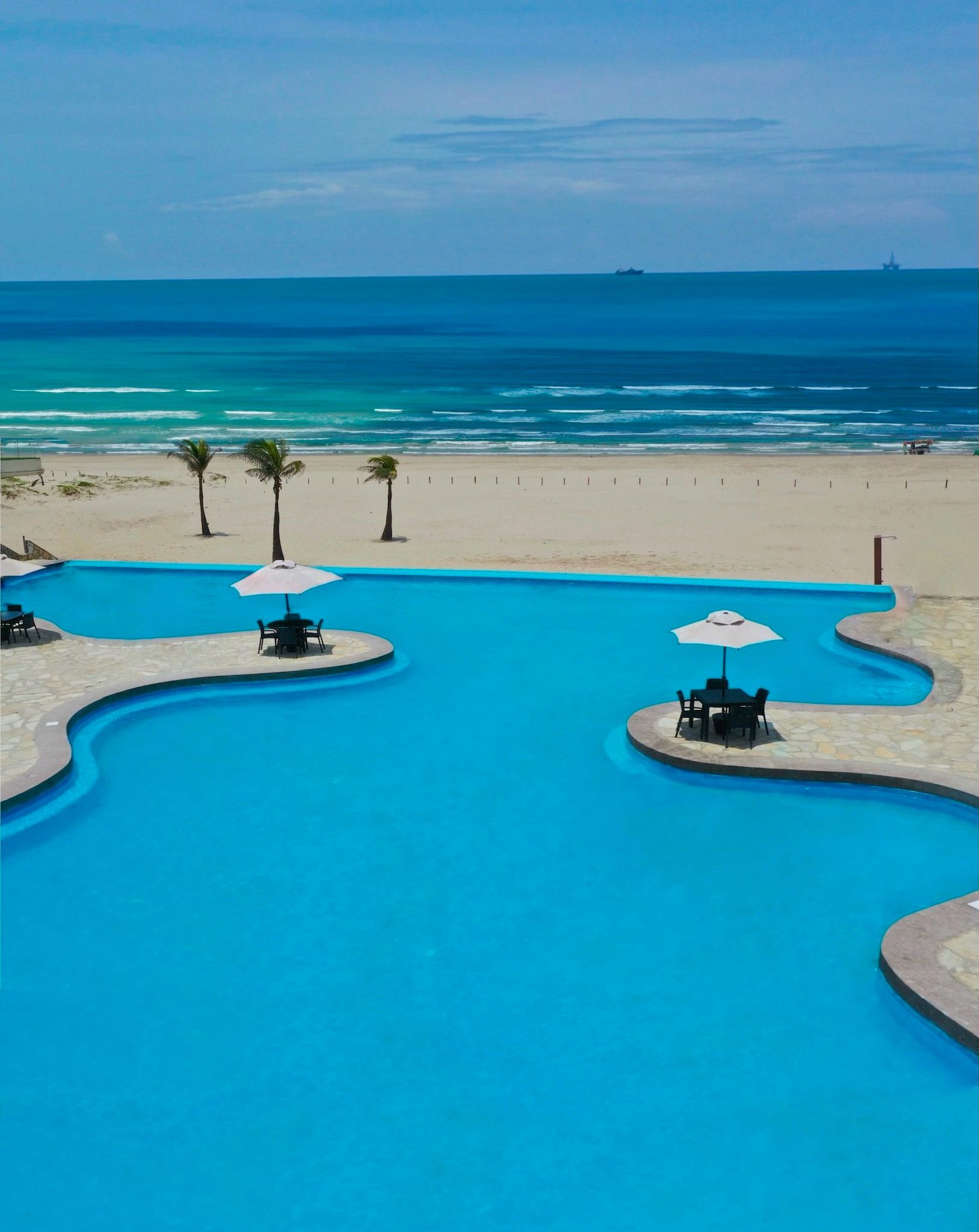 An aerial view of a large swimming pool next to a beach.
