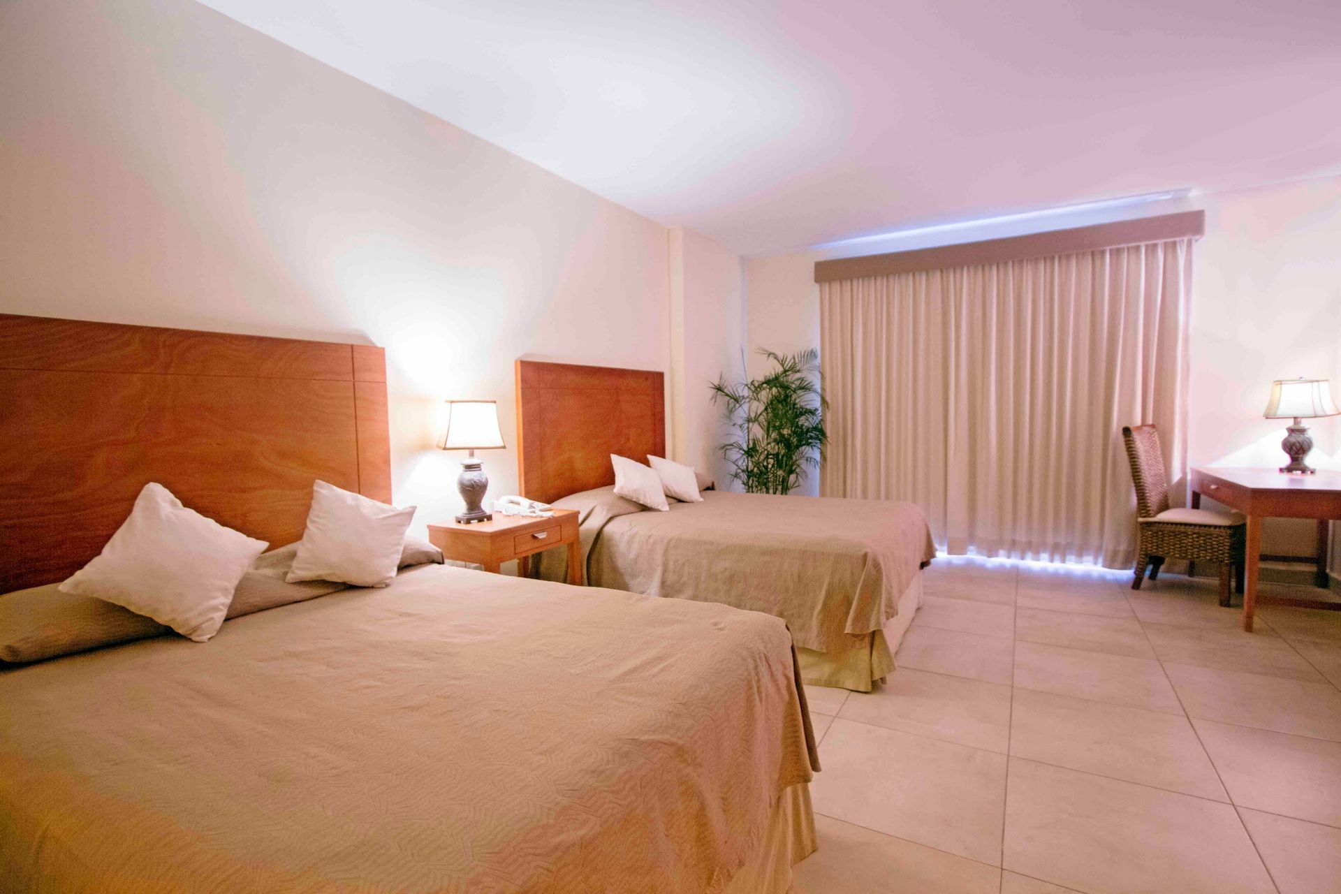 A hotel room with two beds , a desk and a chair.