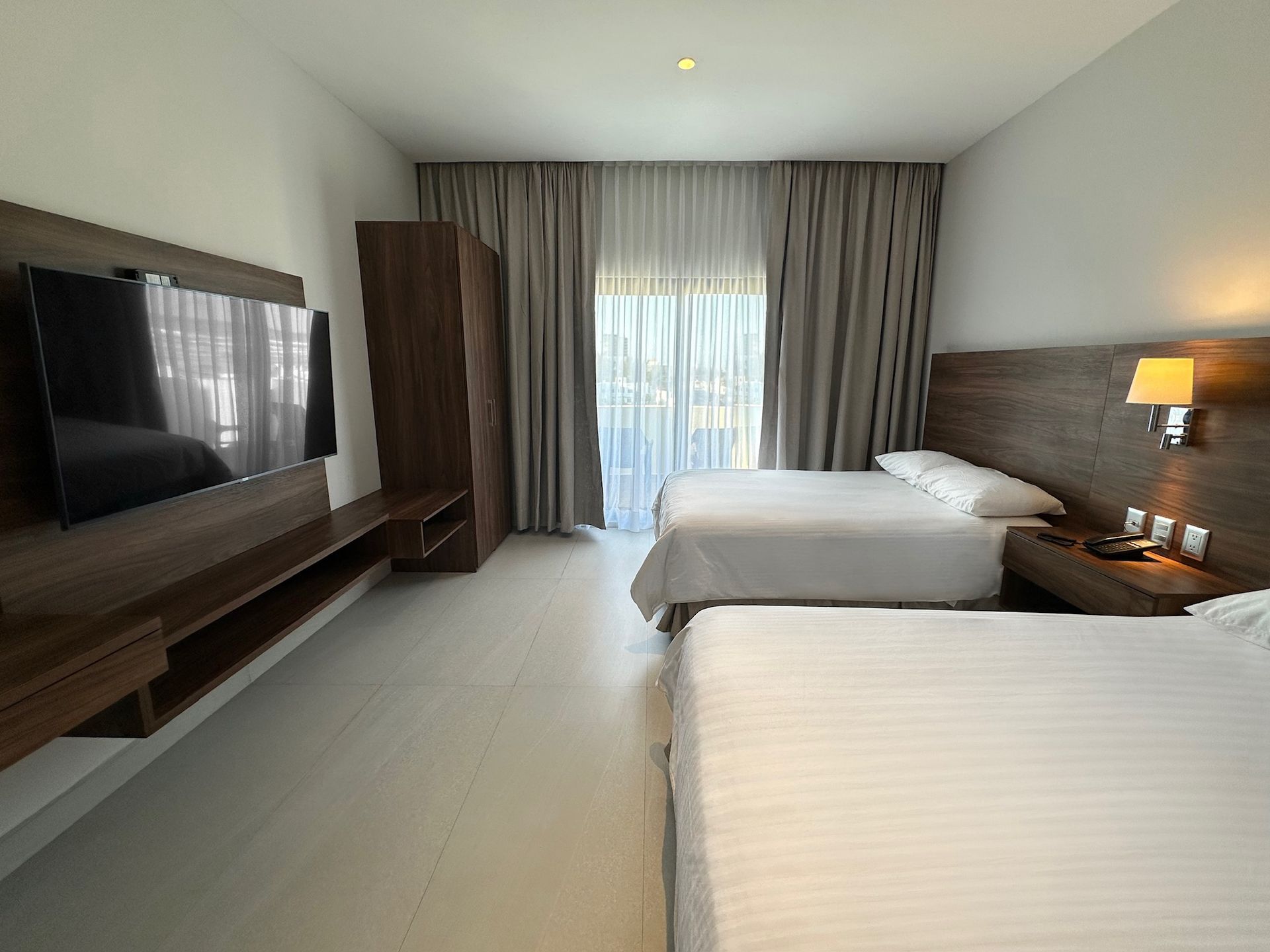 A hotel room with two beds and a flat screen tv