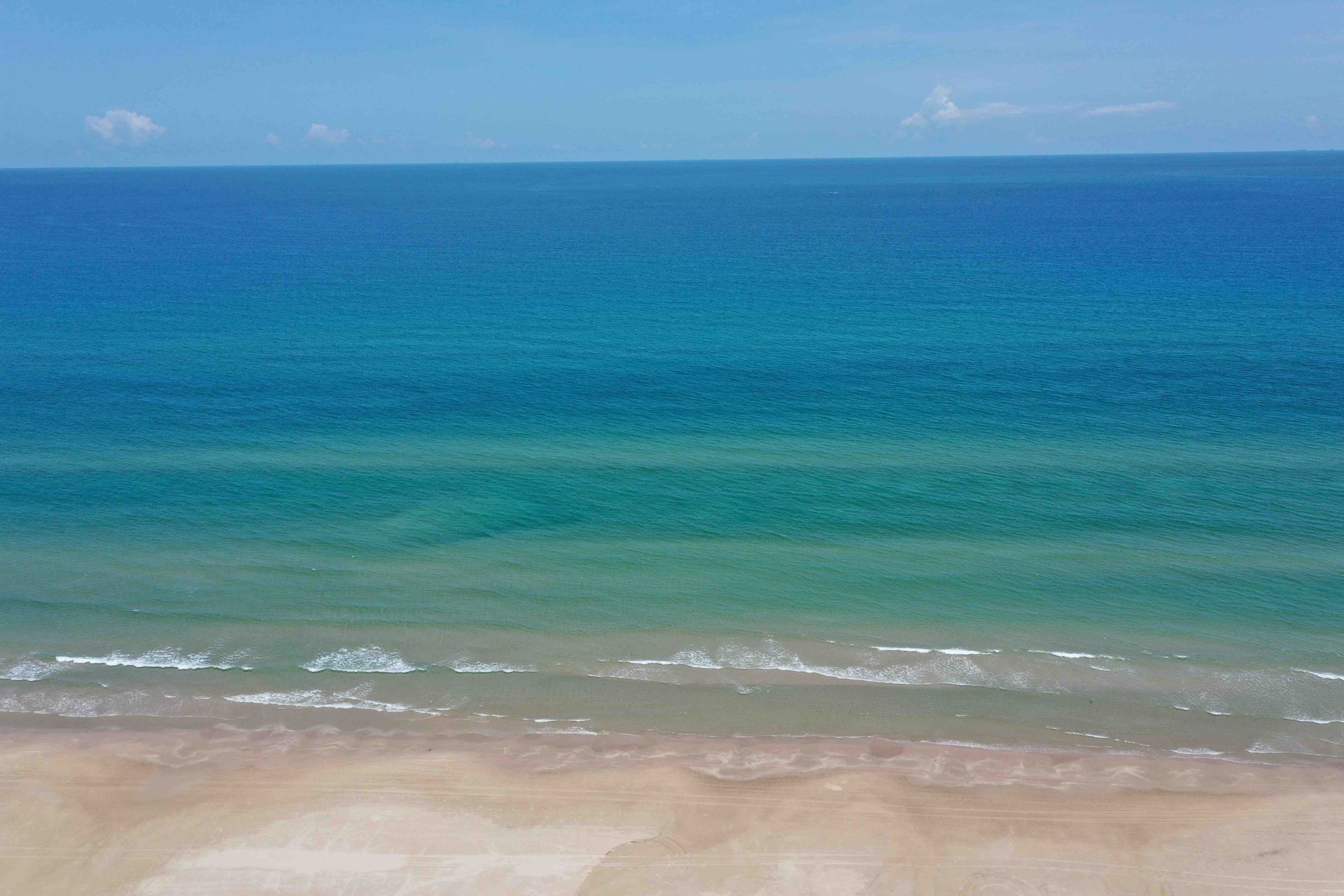 A view of the ocean from a beach on a sunny day.