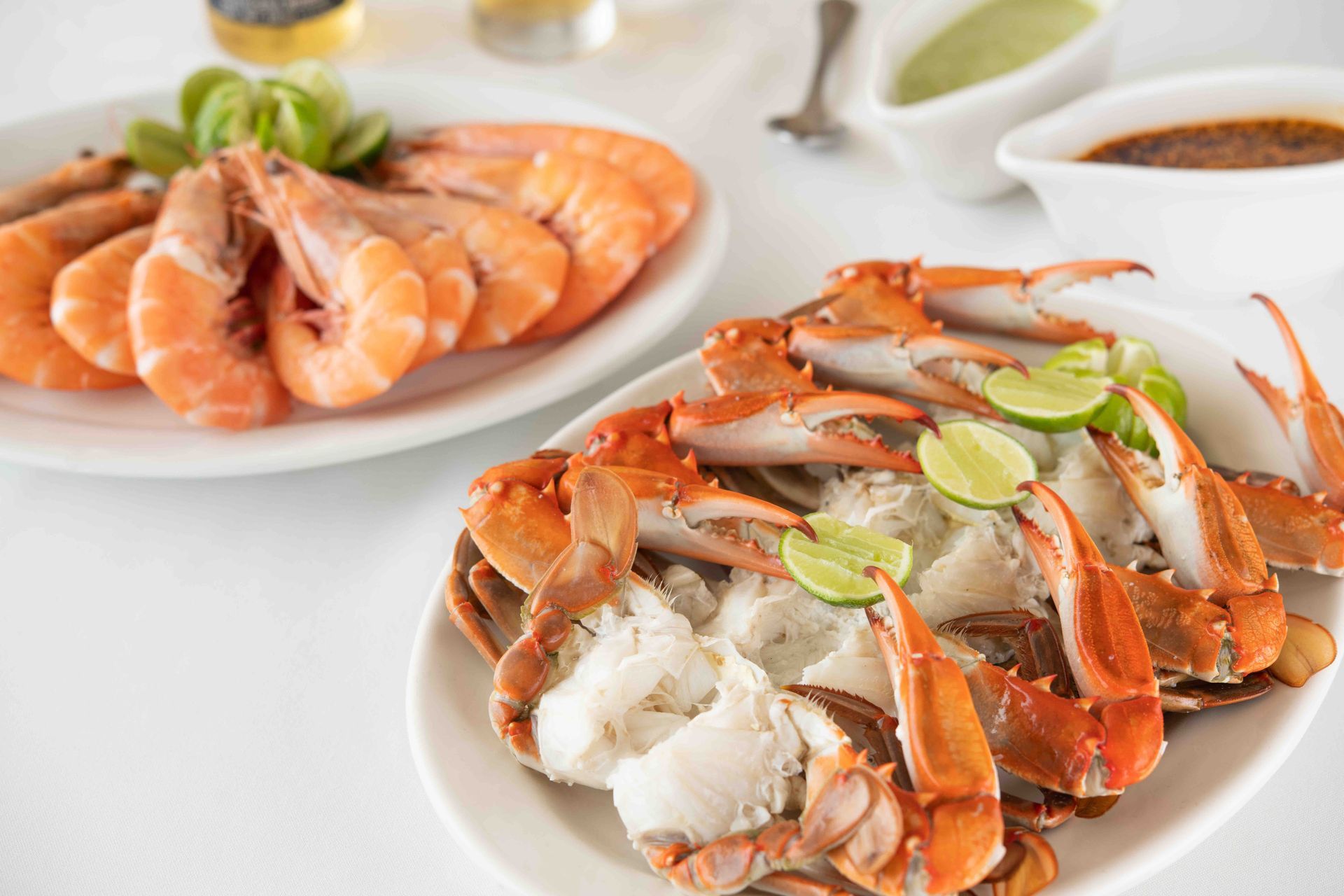 There are two plates of shrimp and crabs on the table.