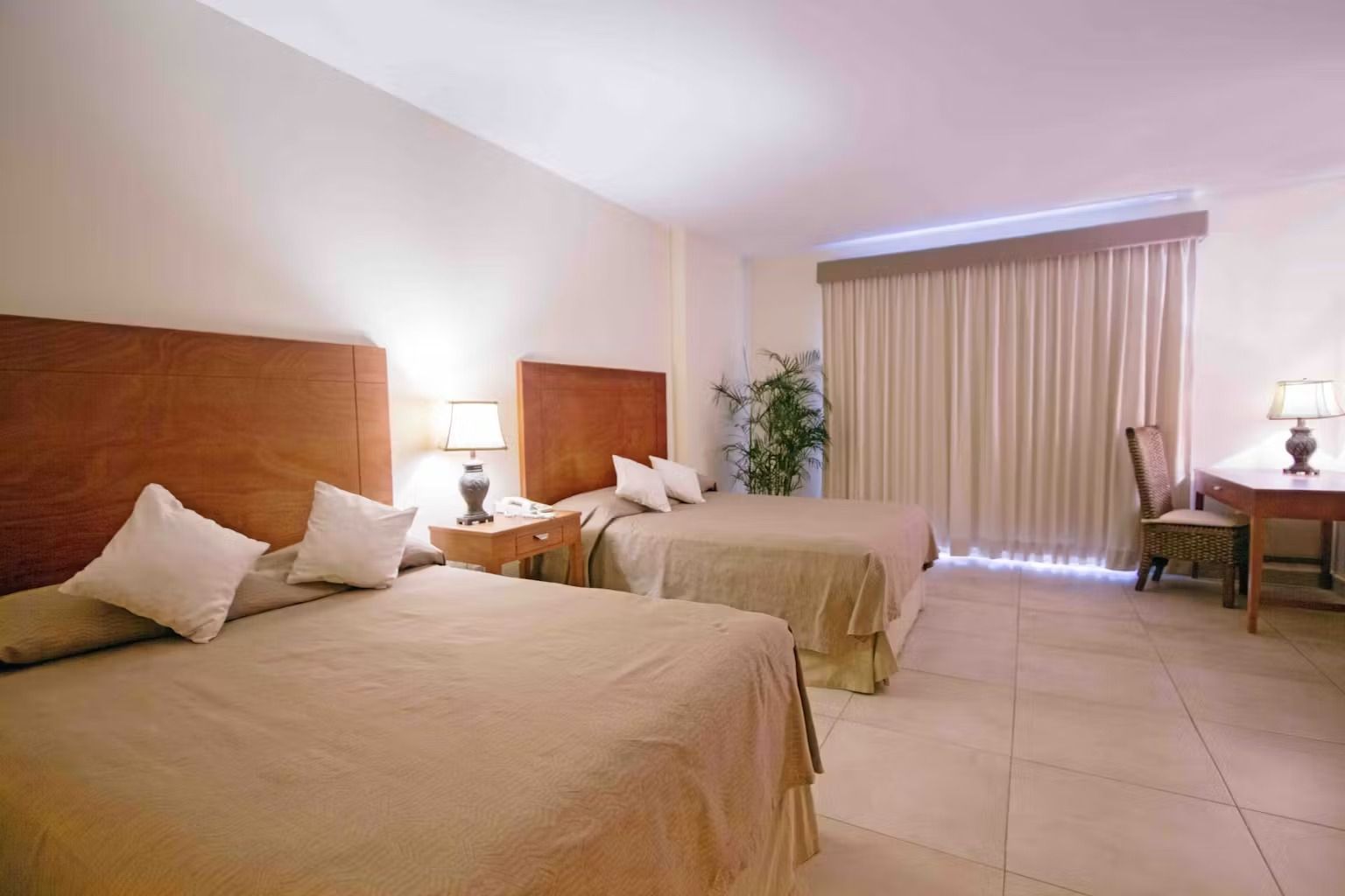 A hotel room with two beds , a desk and a chair.