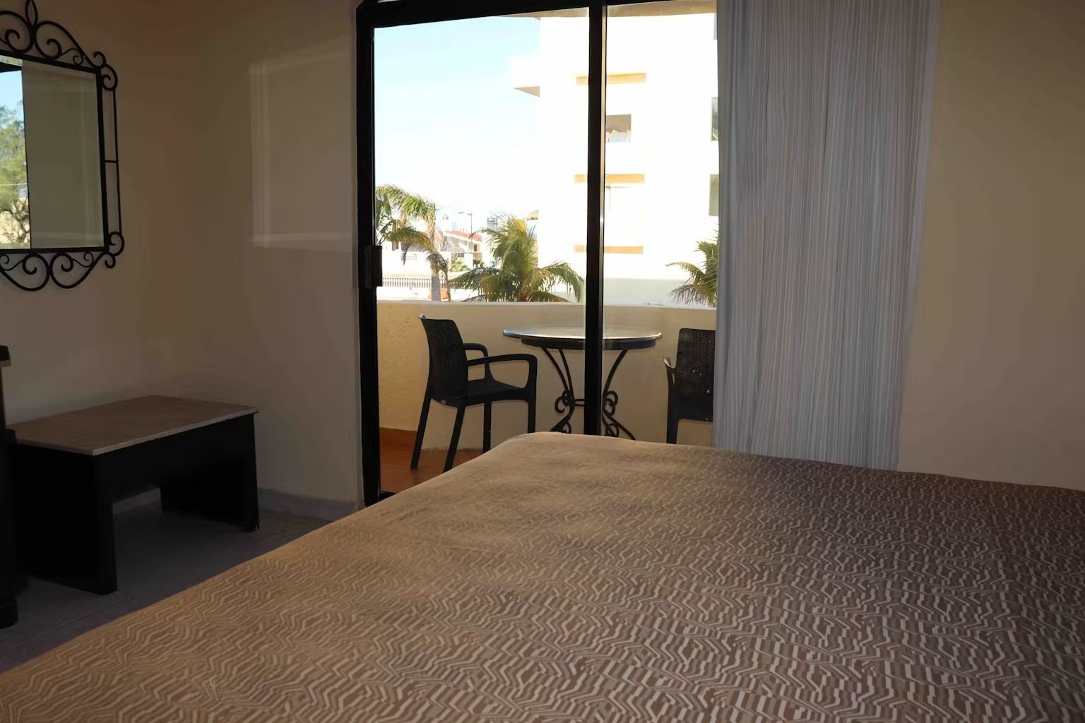 A hotel room with a sliding glass door leading to a balcony.