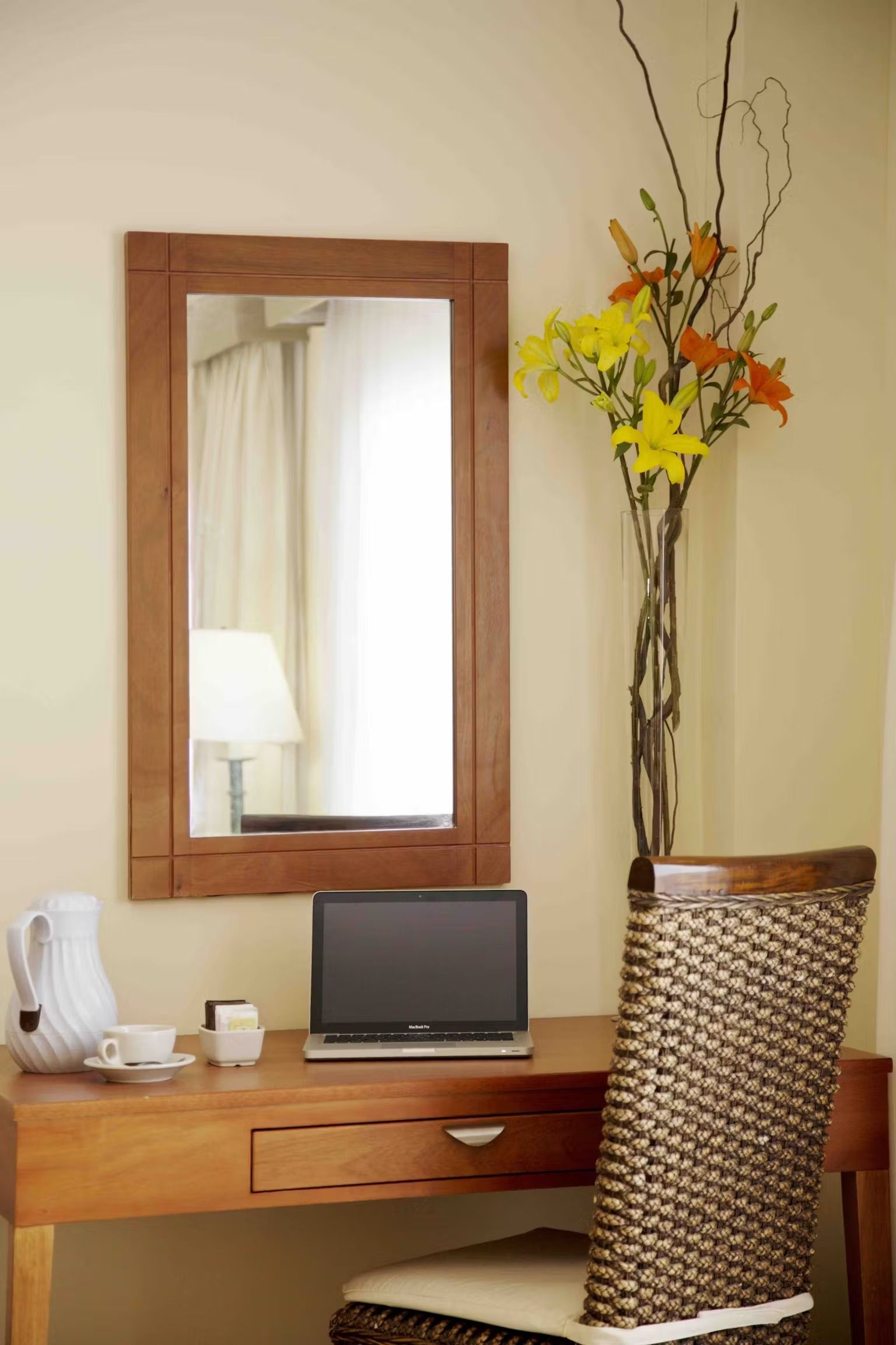 A desk with a laptop and a vase of flowers on it