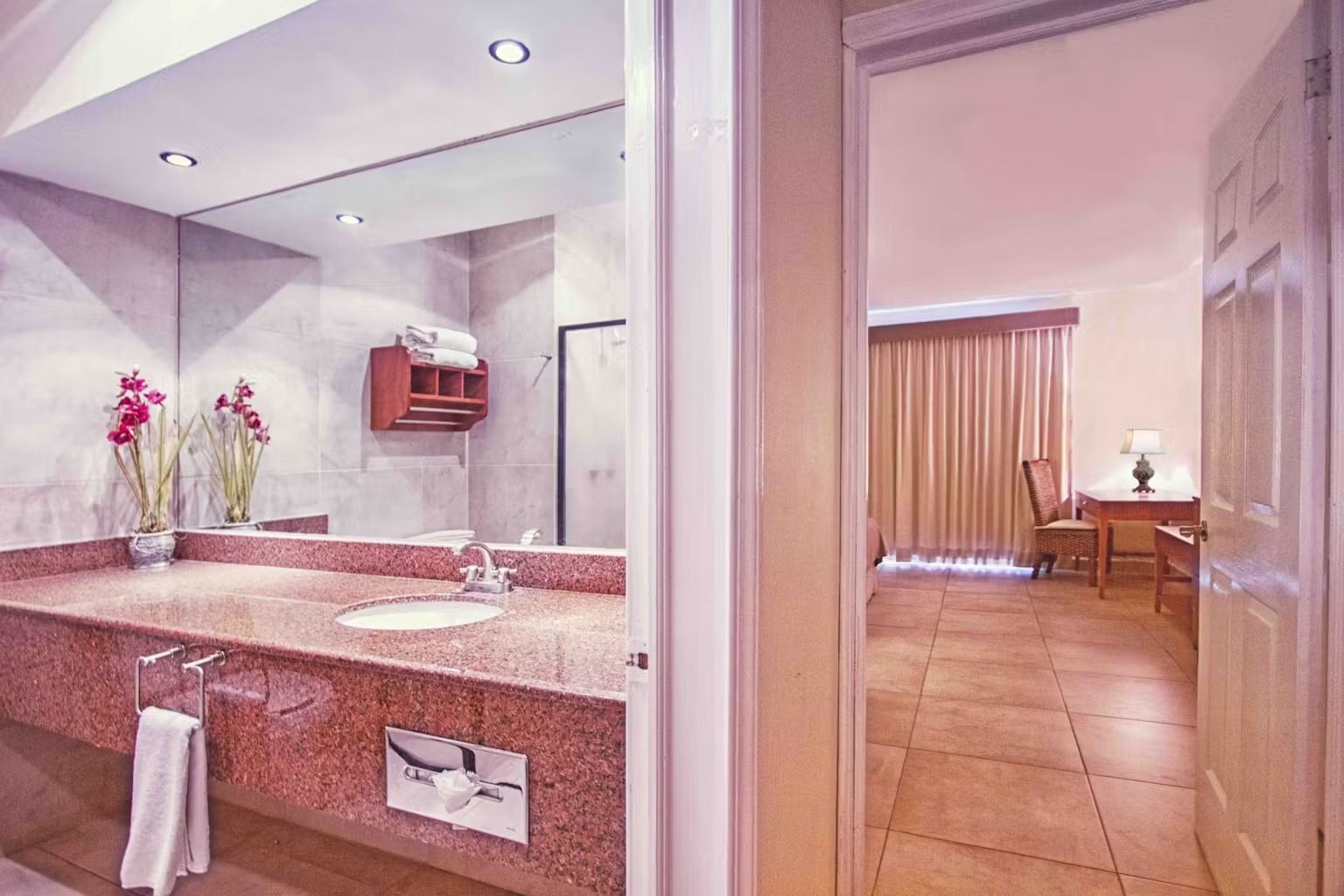 A bathroom in a hotel room with a sink and a mirror.