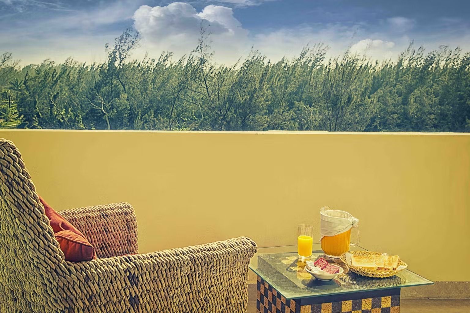 A chair and a table with a pitcher of orange juice on it.