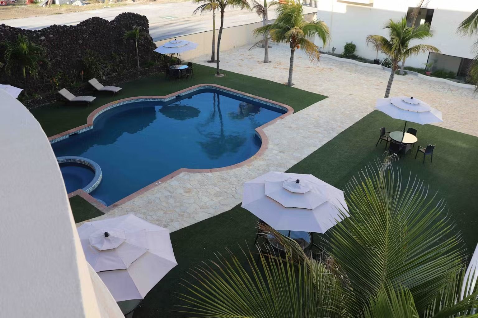 A large swimming pool surrounded by palm trees and umbrellas