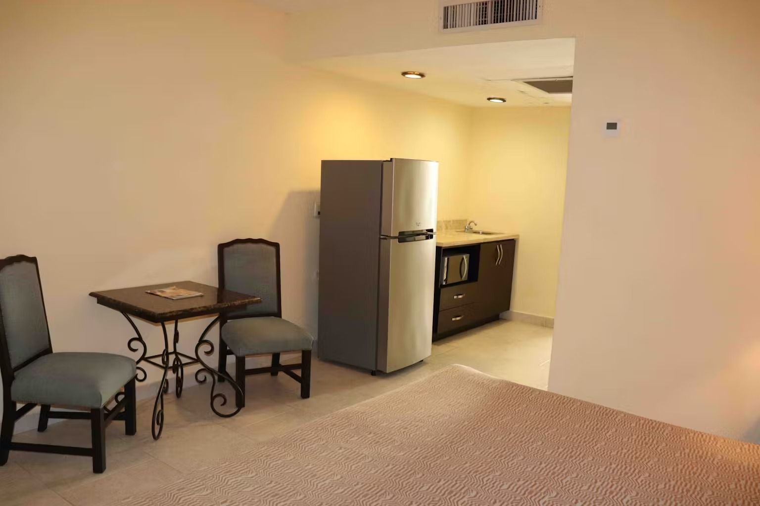 A room with a table and chairs and a refrigerator.
