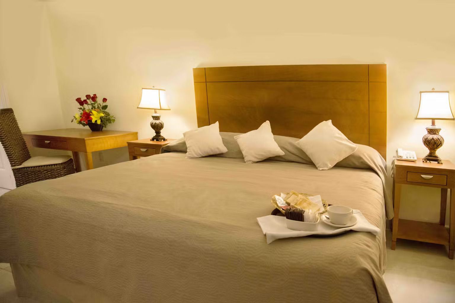 There is a tray of food on the bed in the hotel room.