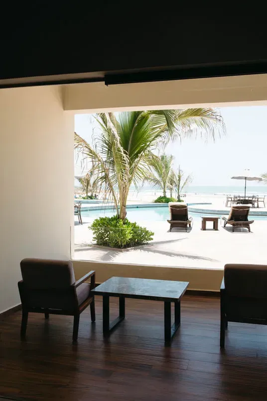 A room with two chairs and a table with a view of a swimming pool.