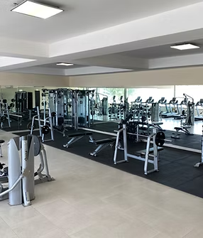 A large gym filled with lots of exercise equipment and mirrors.