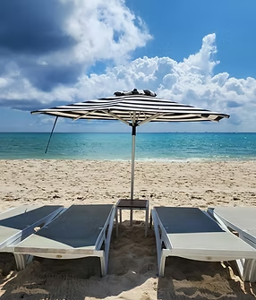 A black and white striped umbrella is sitting on top of a sandy beach.