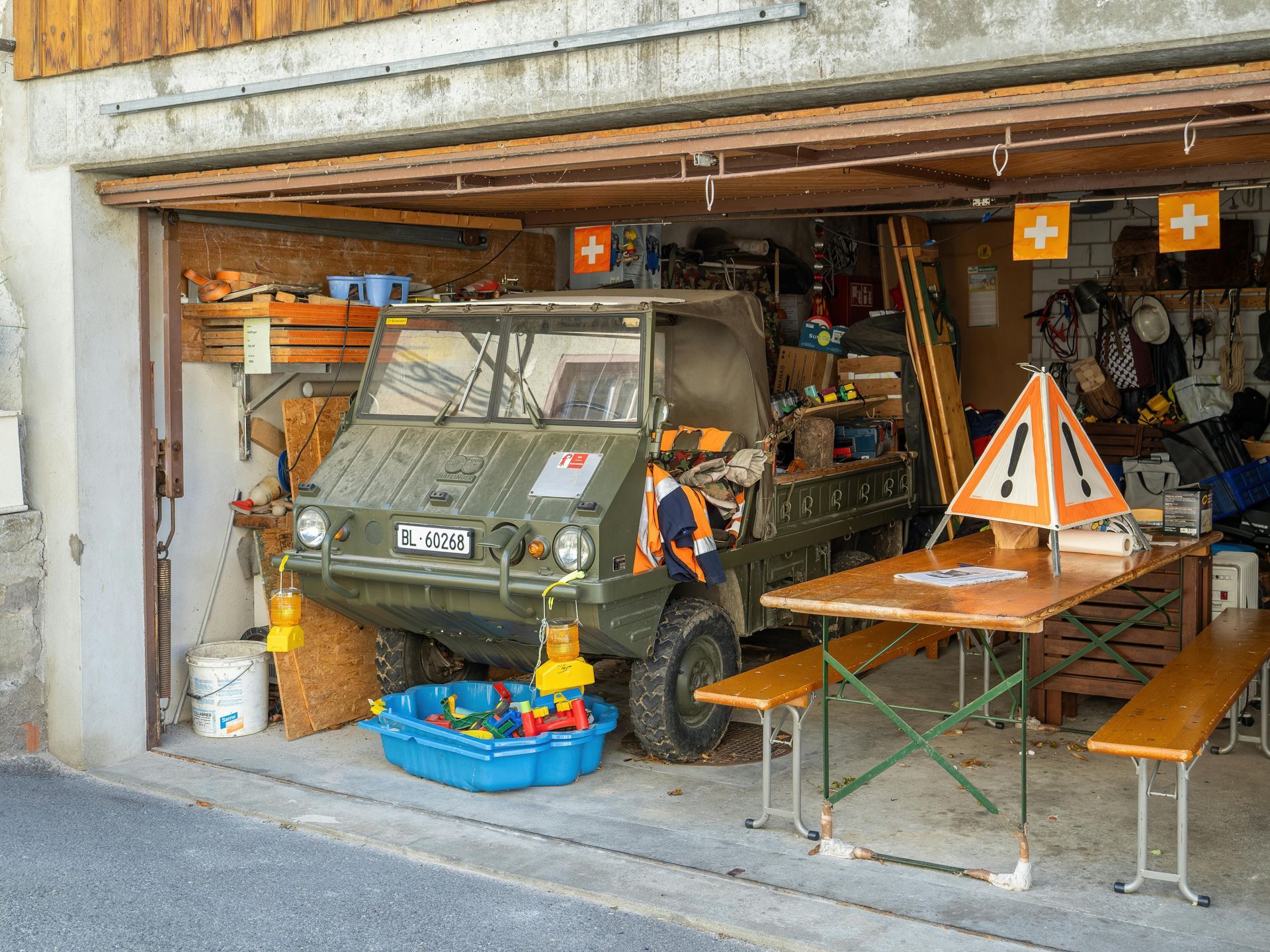 Garage with a small vehicle, picnic table, and bright orange safety signs inside.