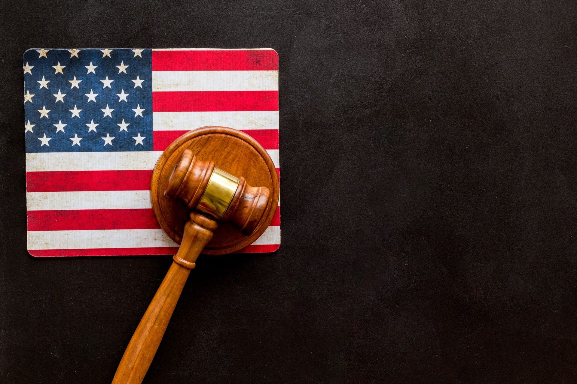 Judge’s gavel on an American flag against a dark background