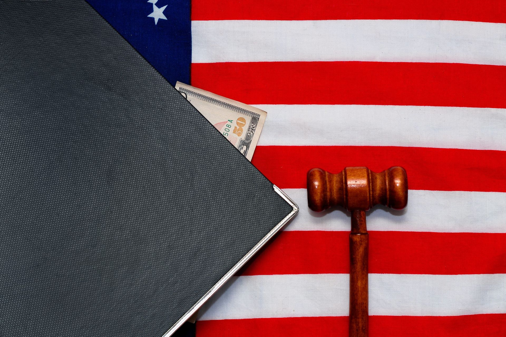 U.S. flag background with a gavel and law books on a dark textured surface