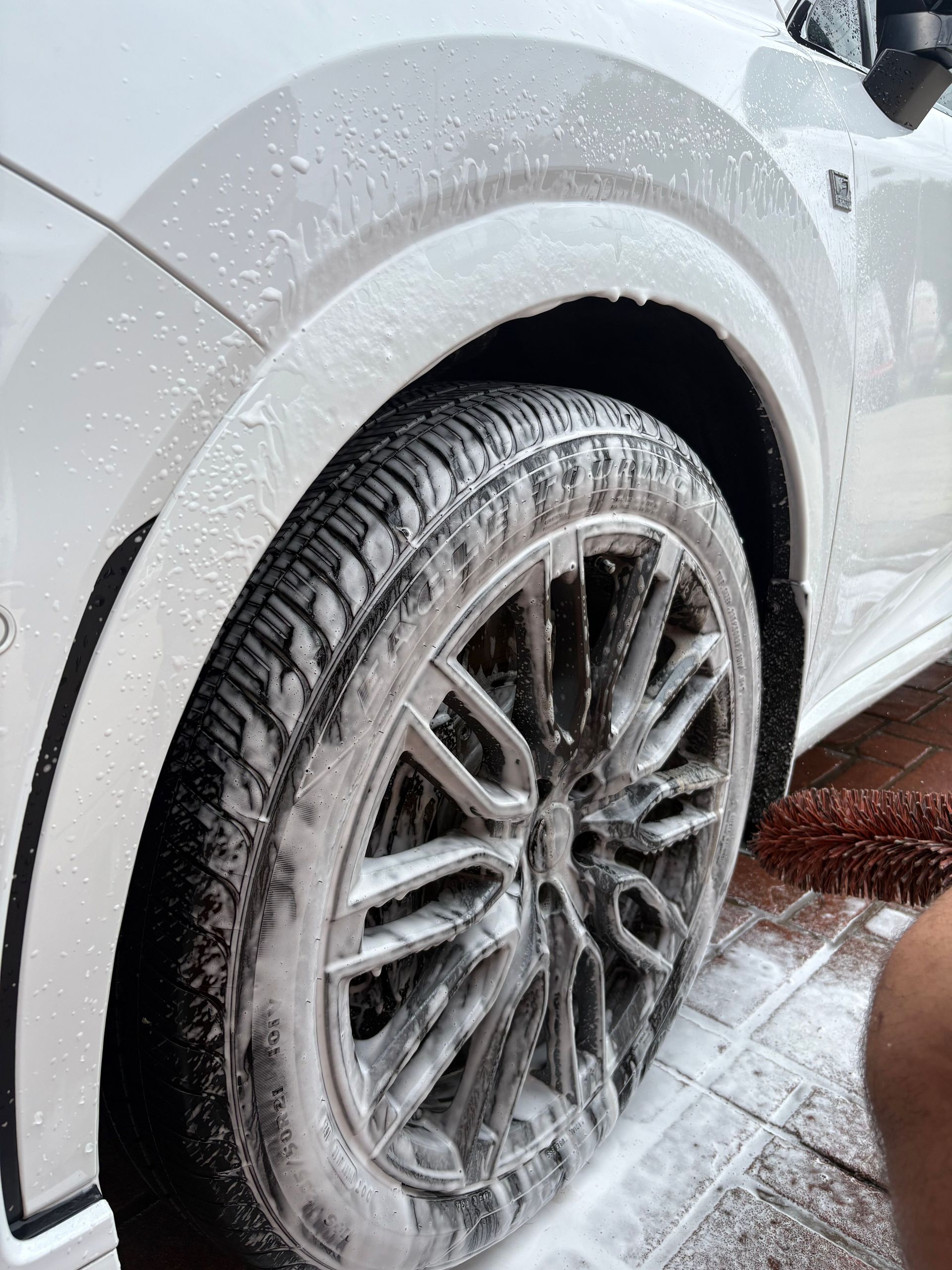 Silver car wheel covered in snow and slush, parked on a wet driveway