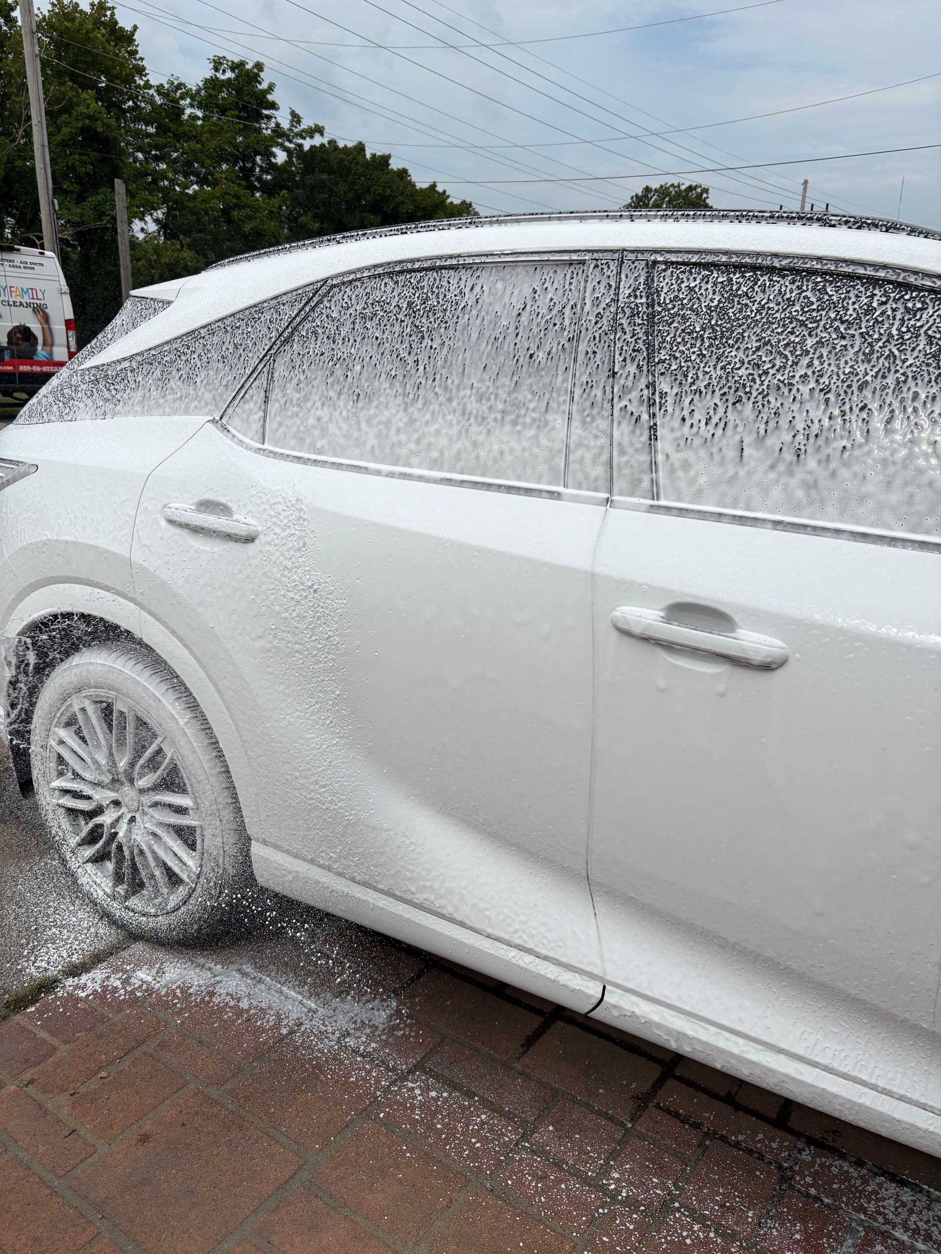White car covered in foam during a wash outdoors