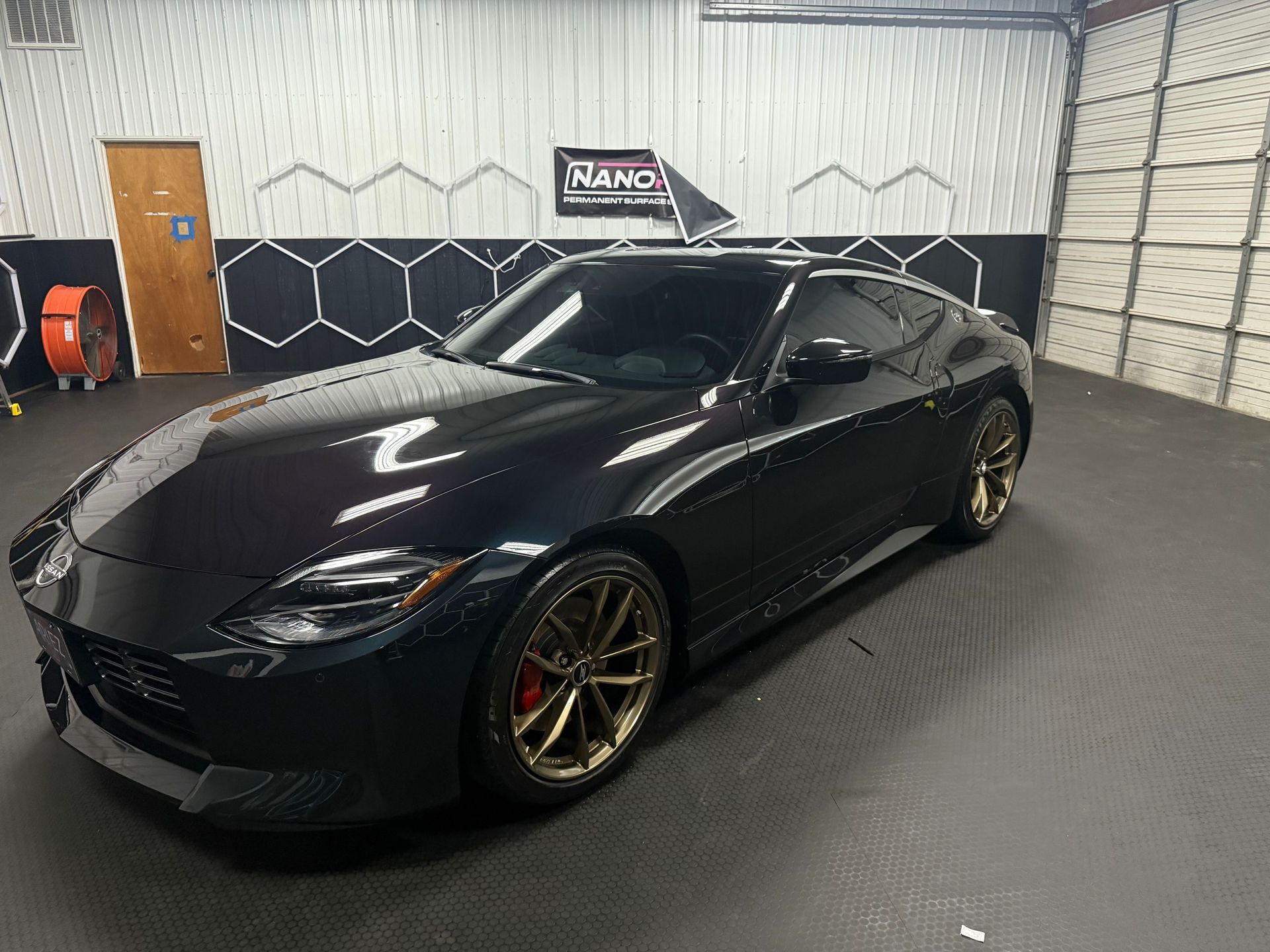 Black sports coupe with gold rims parked inside a garage
