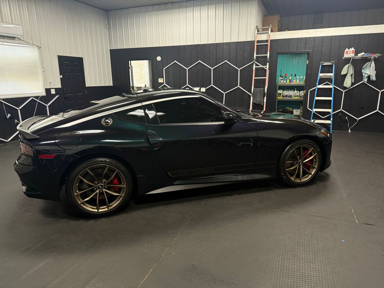 Black sports car in a garage with hexagon wall decor and shelves in the background