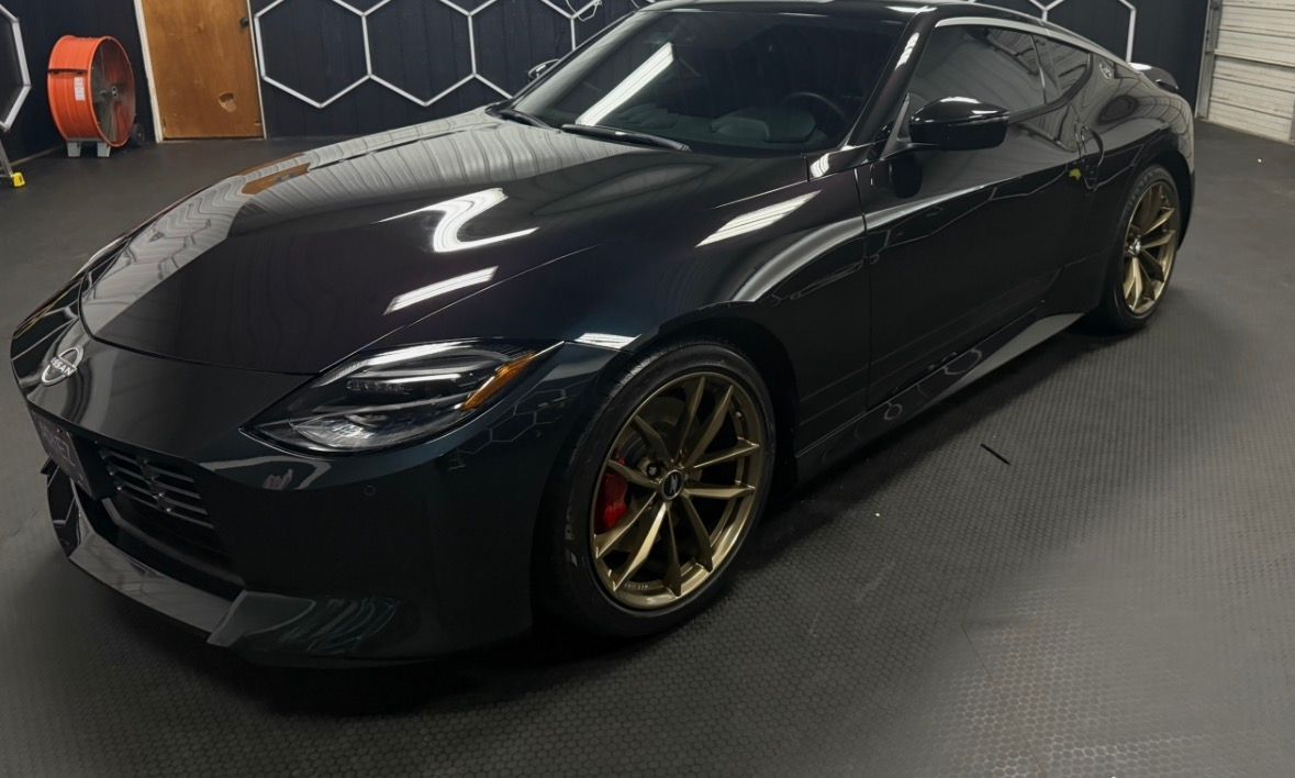 Black sports coupe parked indoors on a dark carpeted floor.