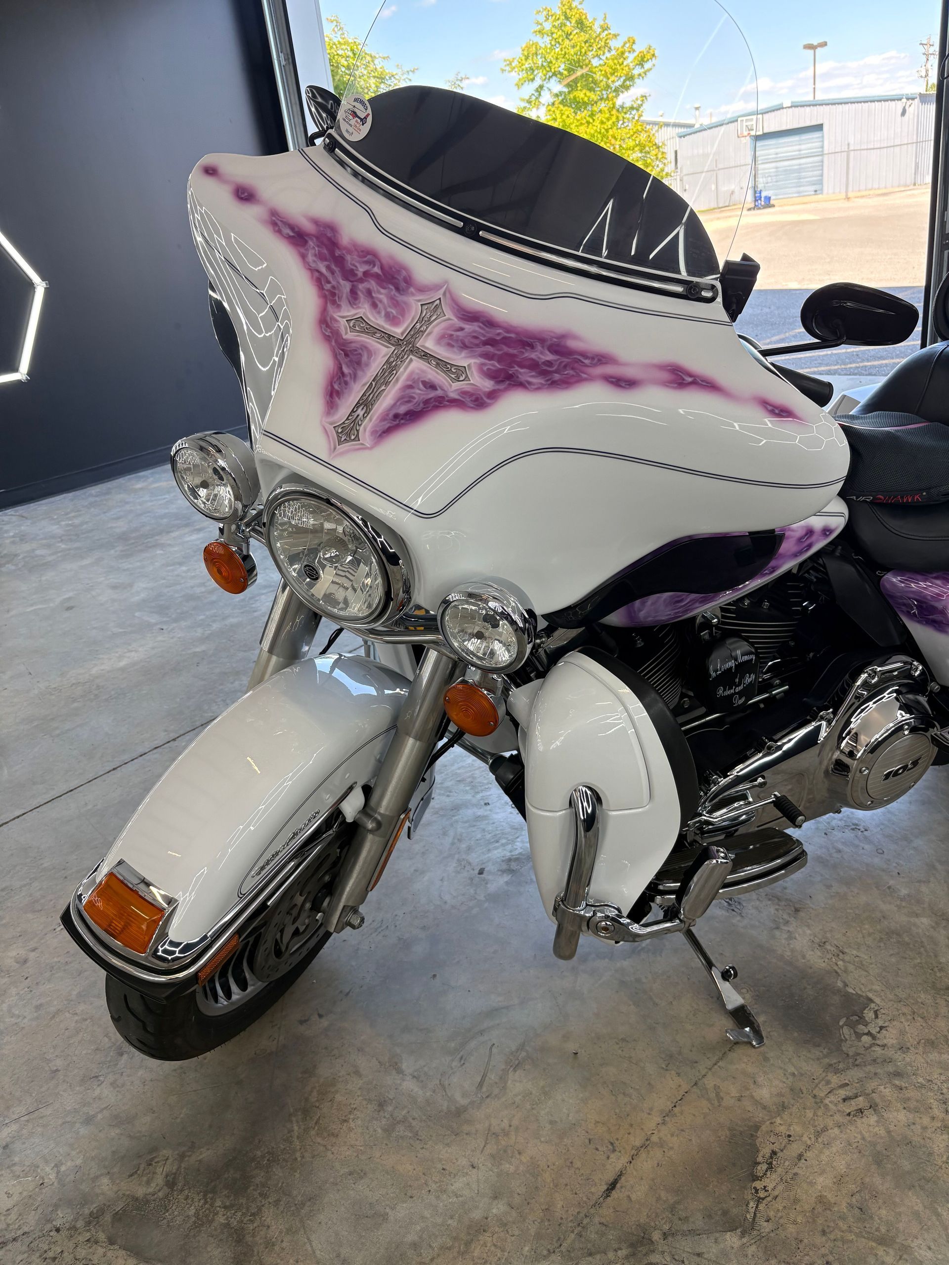 White motorcycle with purple star accents parked indoors, front view.