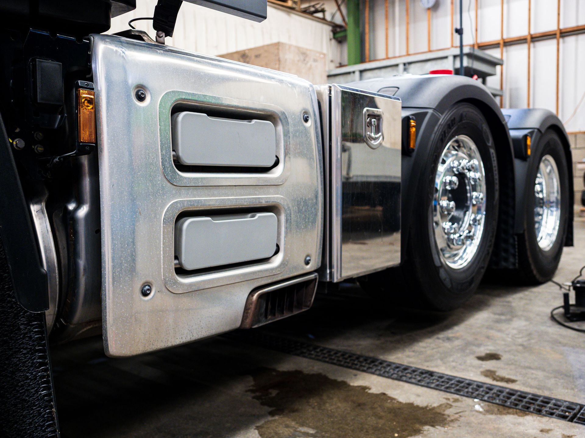 Chrome semi-truck cab side panel with dual rear wheels in a garage