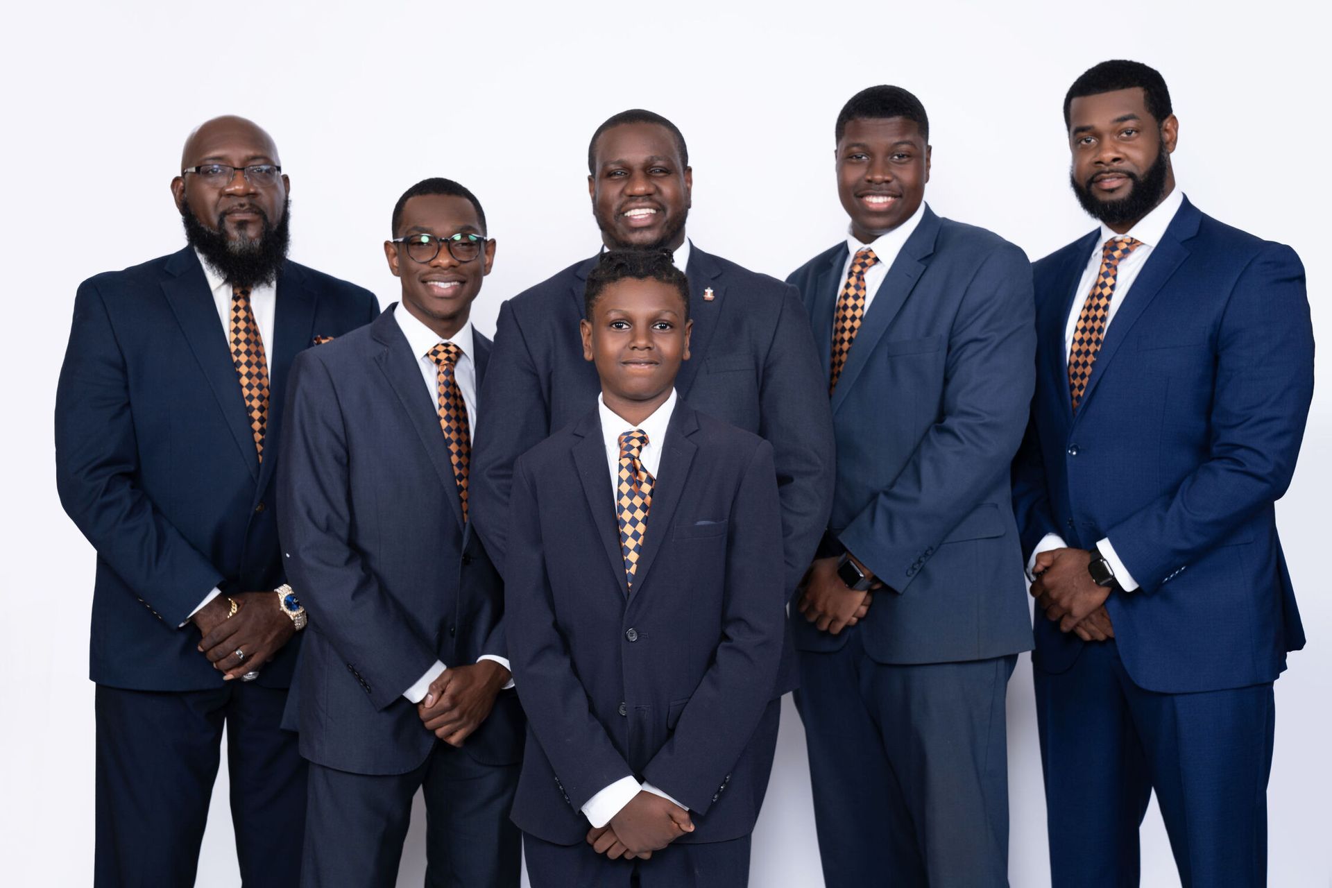 Group of six people in suits, posing against a white background; all wearing orange and gold ties.