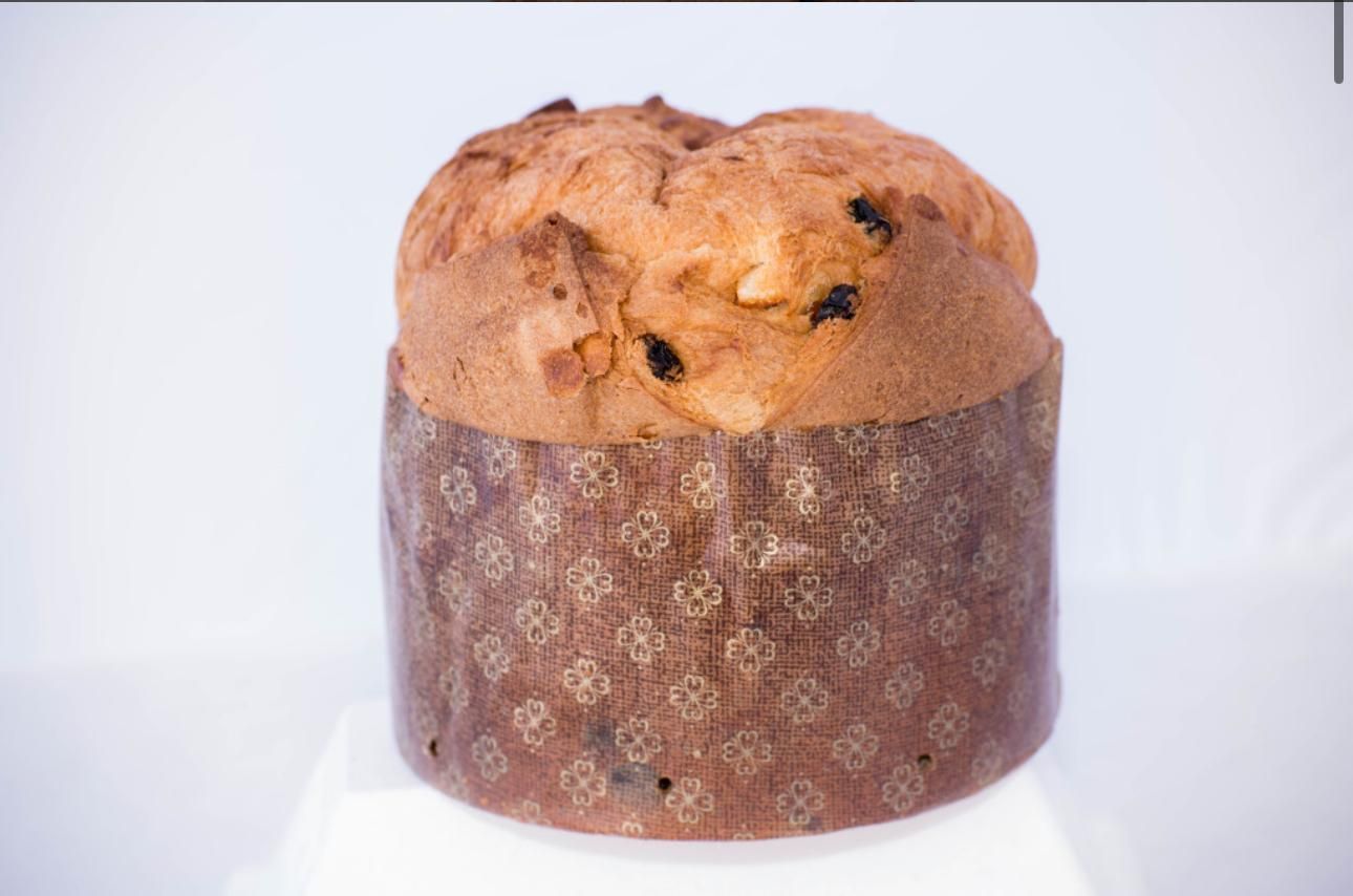Panettone in un involucro di carta decorativa, sfondo chiaro.