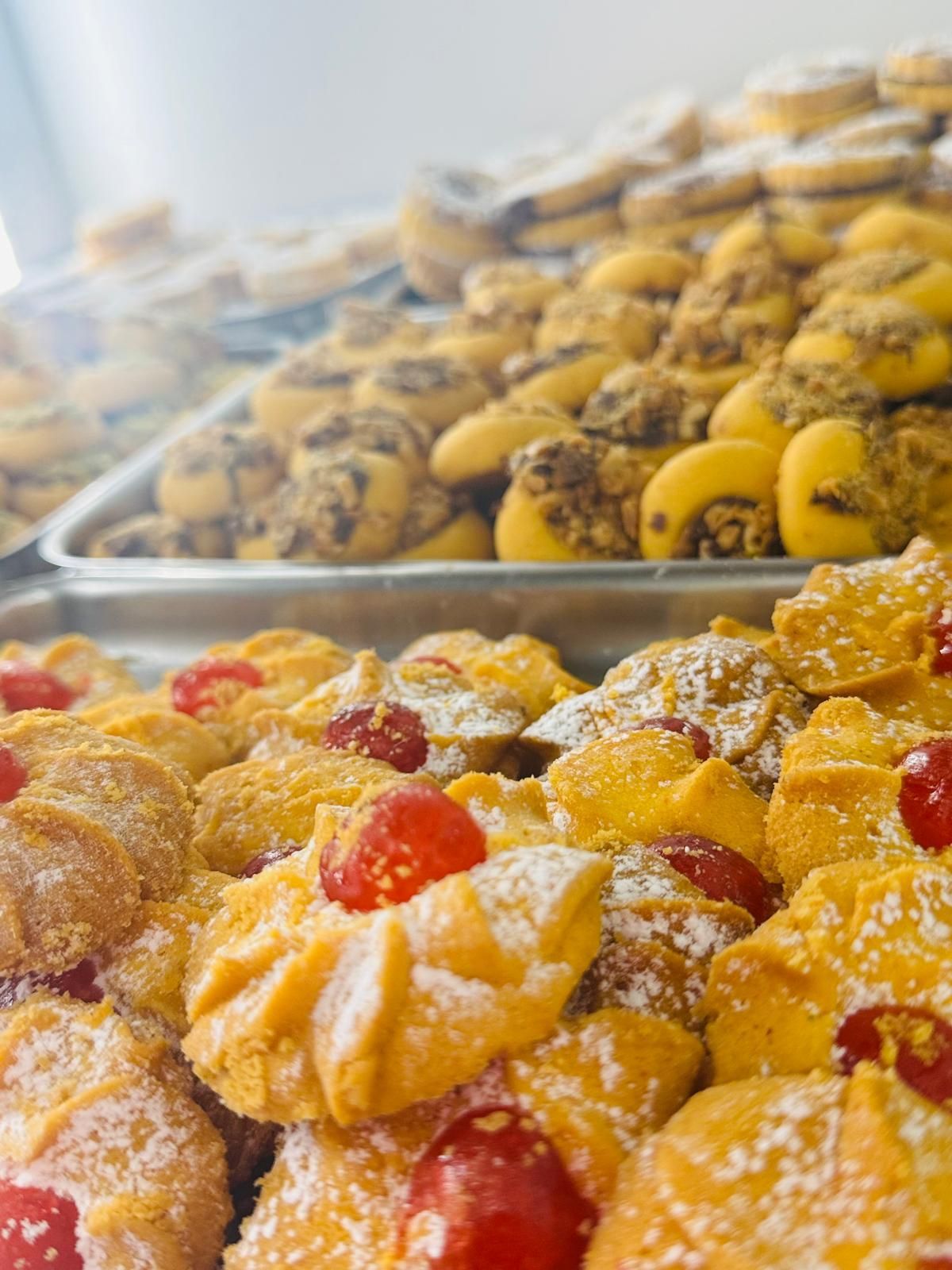 Assortimento di biscotti, primo piano di un vassoio di biscotti ricoperti di ciliegie e zucchero a velo, in una pasticceria.