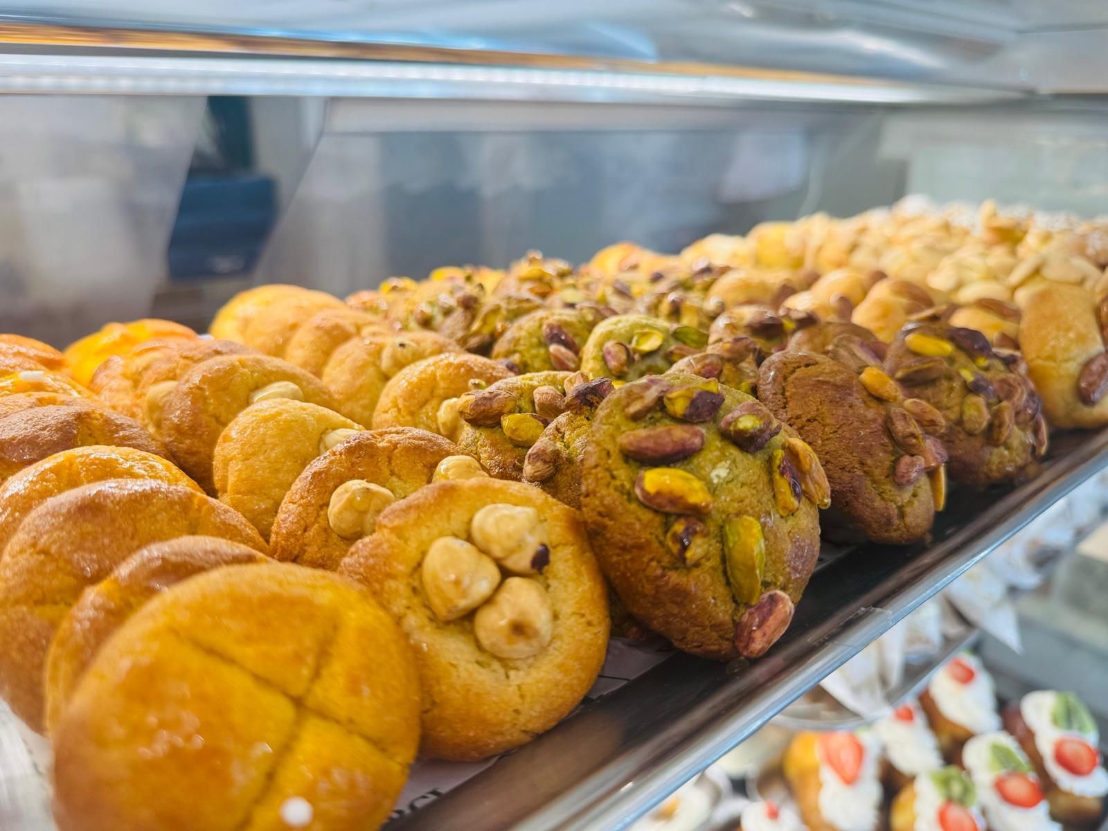 File di pasticcini italiani in esposizione, con varietà di nocciole, pistacchi e mandorle.