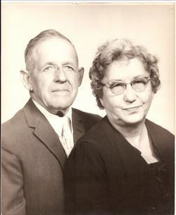 Formal portrait of two adults in dark clothing against a plain light background