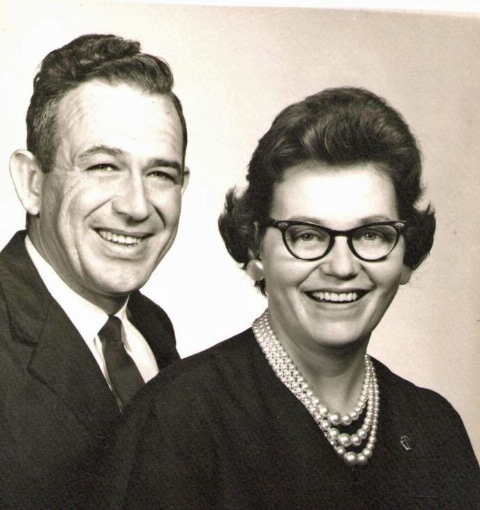 Smiling black-and-white portrait of a man and woman in formal attire, facing the camera