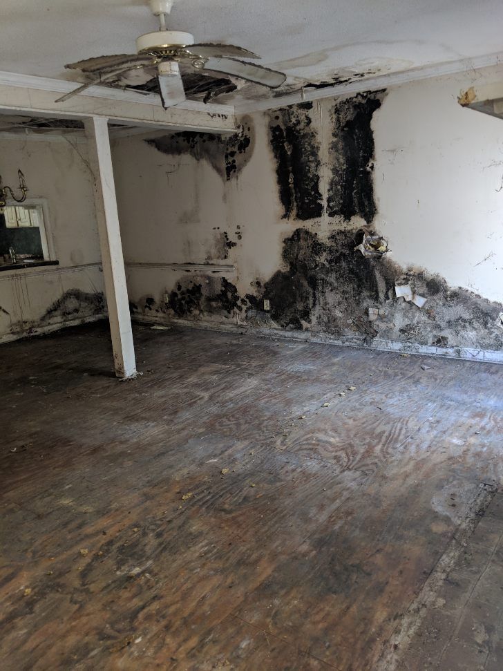 an empty room with a ceiling fan and a hole in the wall