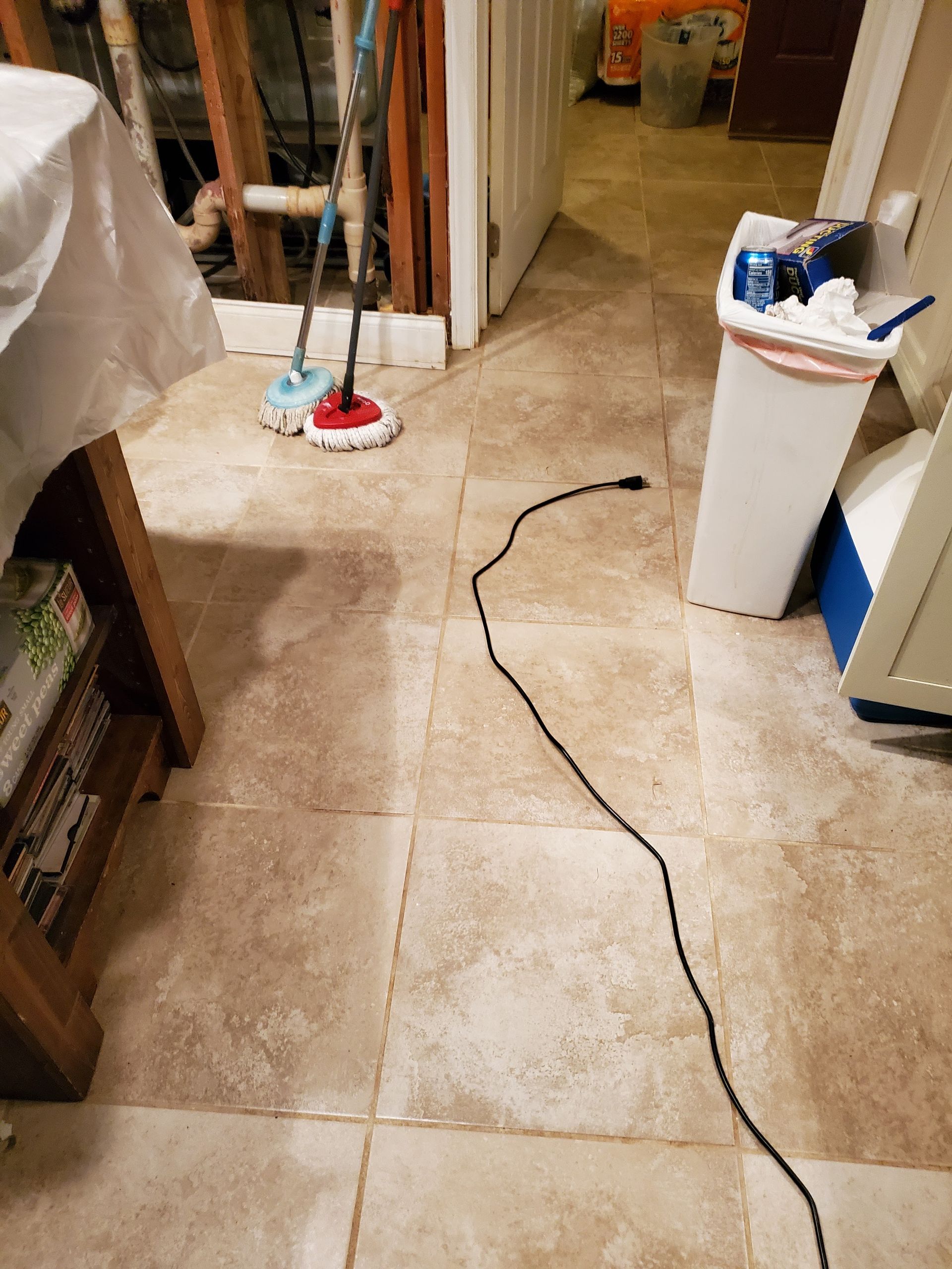 a mop is sitting on a tiled floor next to a trash can