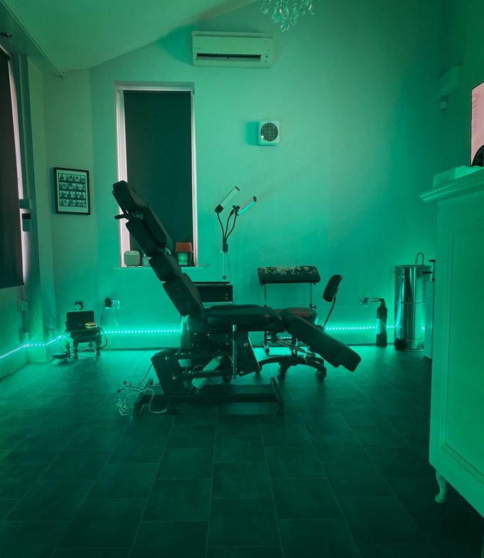 A tattoo chair is sitting in a room with green lights.