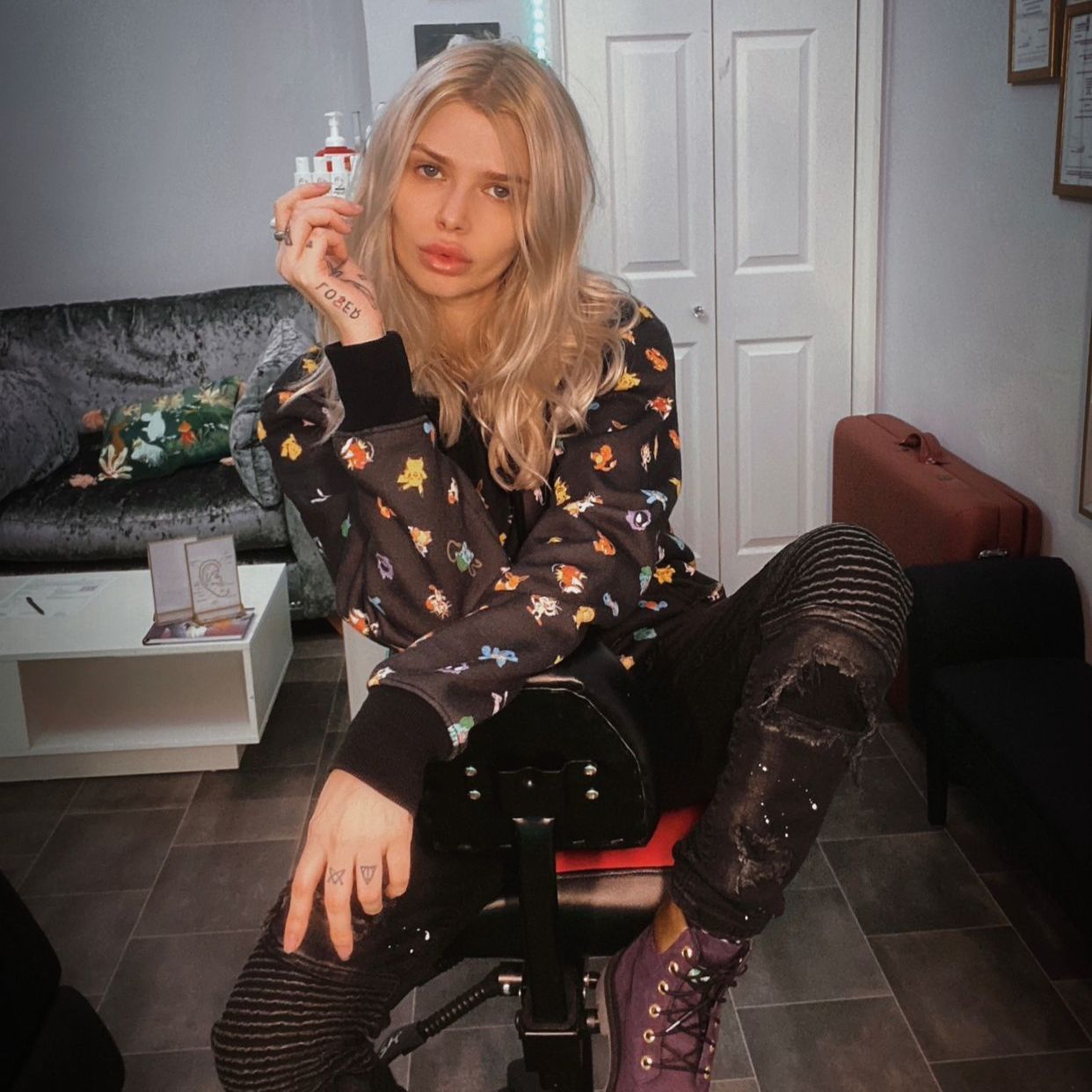 A woman with a tattoo on her hand is sitting on a chair