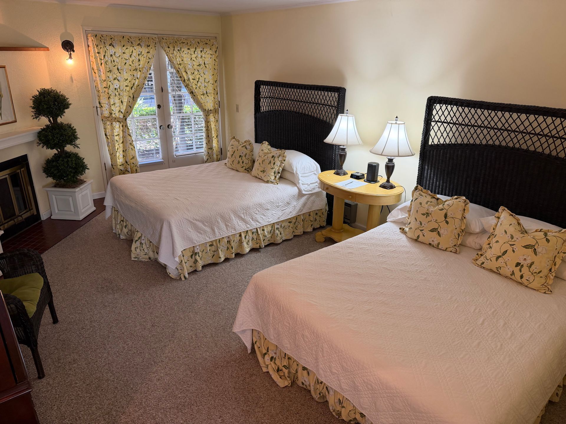 Bedroom with two double beds, yellow accents, and a window with curtains.