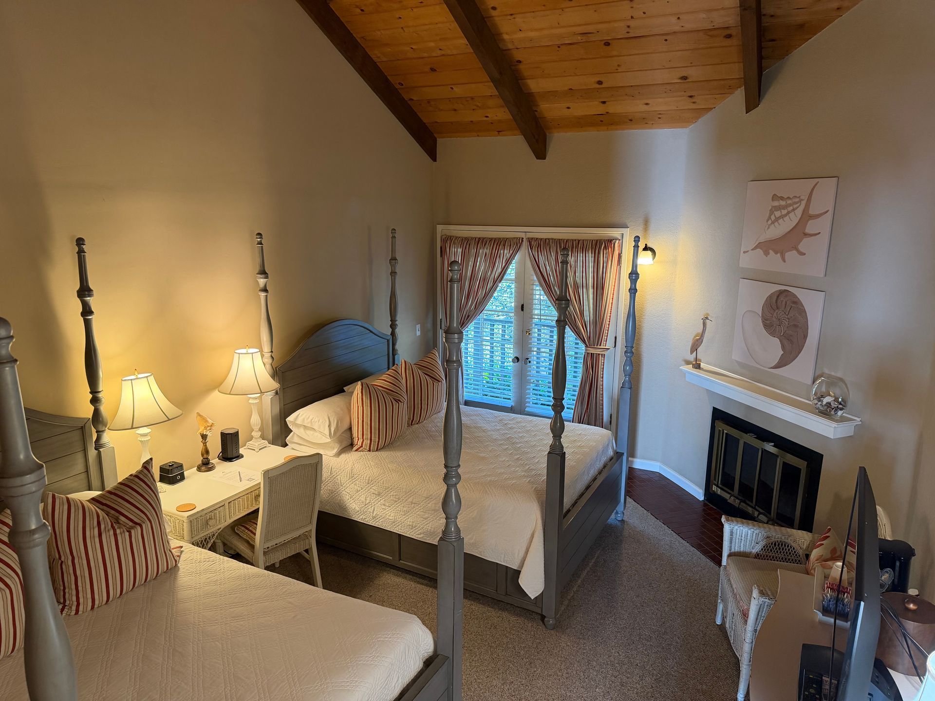 Bedroom with two four-poster beds, a fireplace, and a desk.  The room has a wood-beamed ceiling.