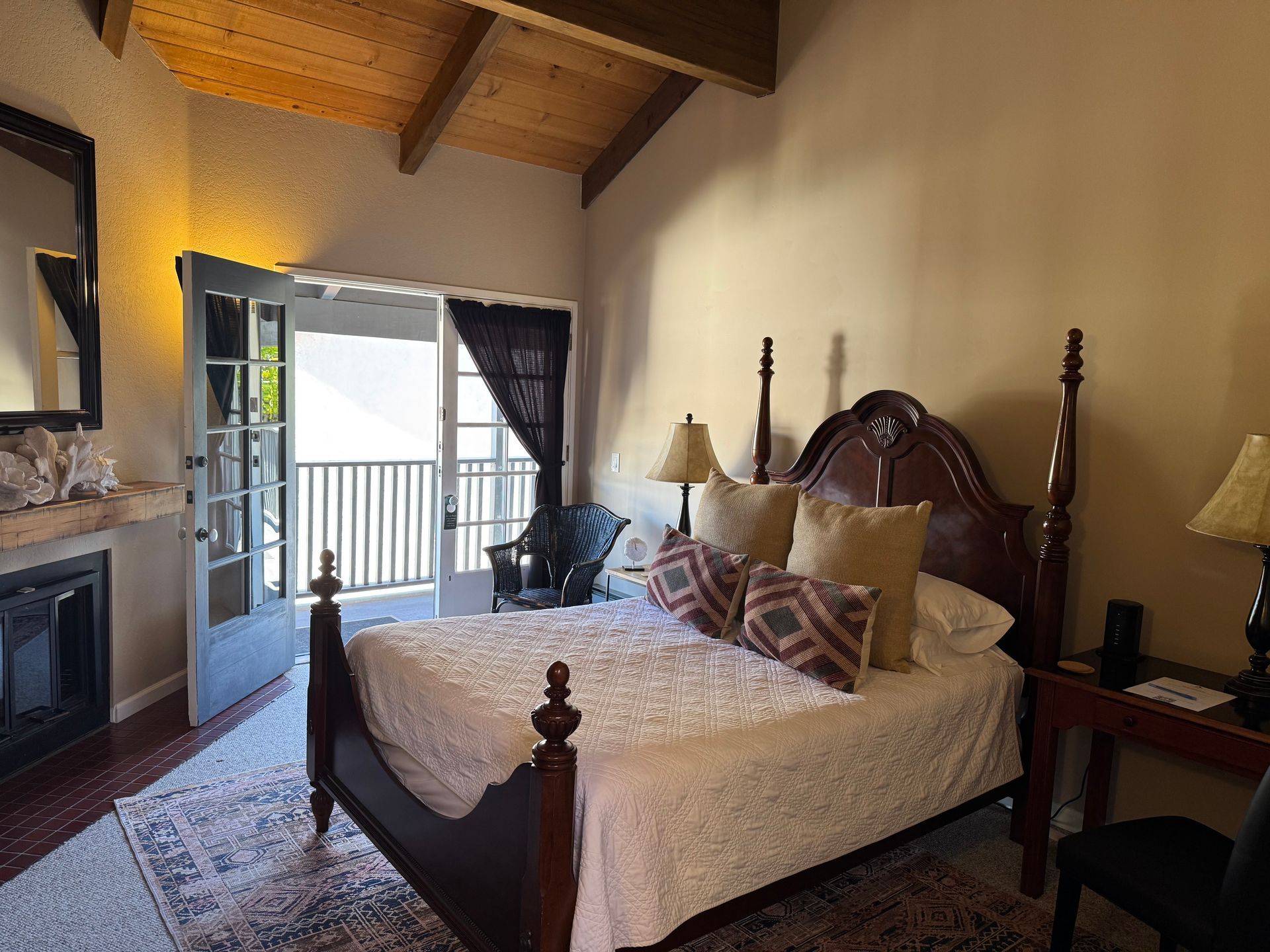 Bedroom with bed, fireplace, and balcony doors.  Wooden bed frame, neutral-toned walls, and rug.