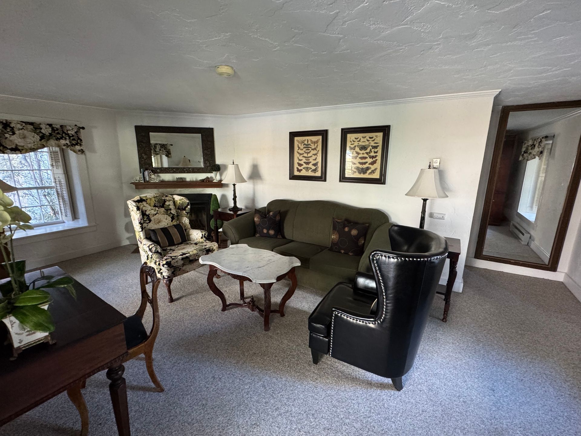 Living room with a sofa, two chairs, a fireplace, and a mirror.