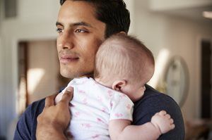 Man holding a sleeping baby in a softly lit room
